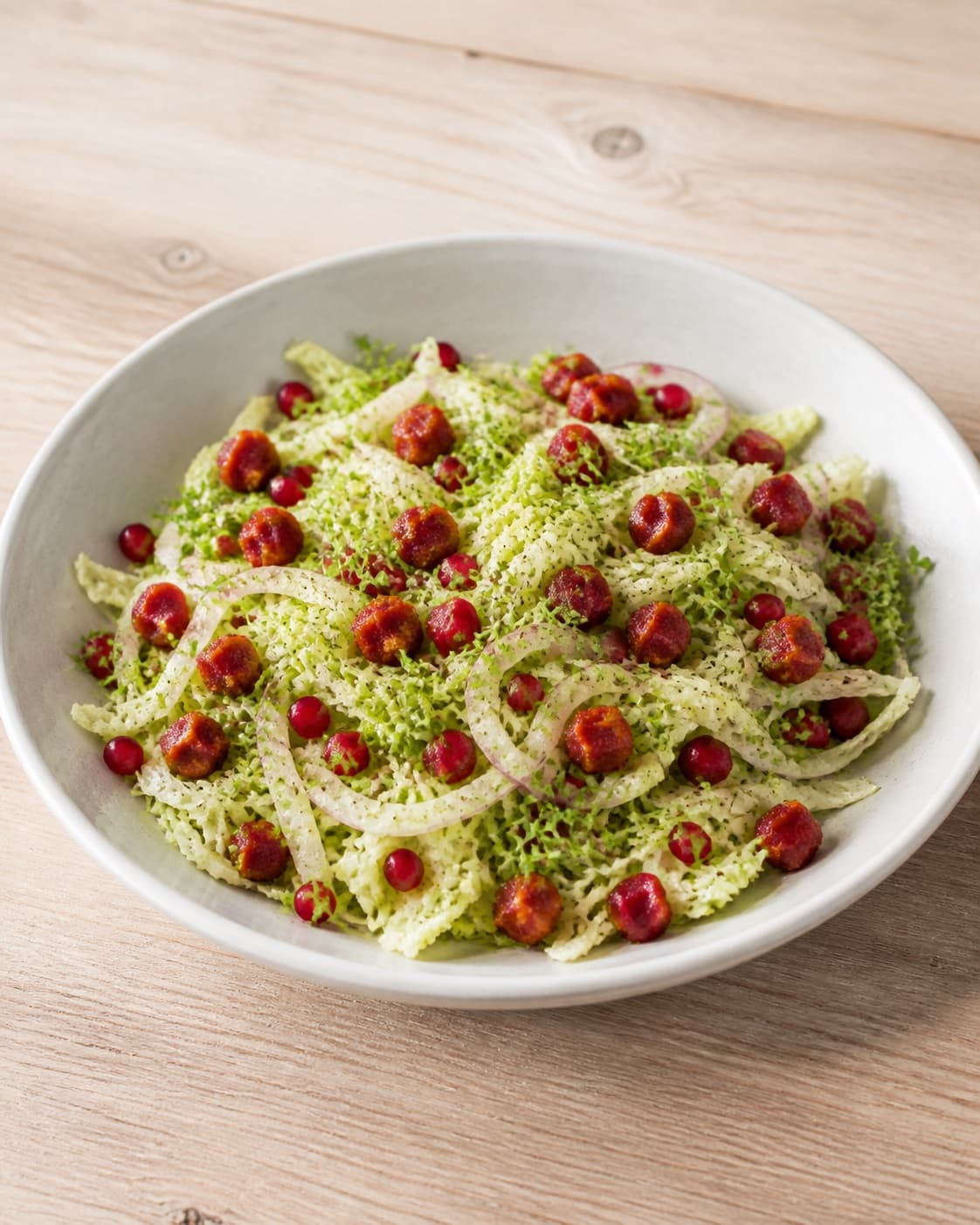One serving platter of pointed-cabbage salad topped evenly with crisp red chorizo cubes, ruby pomegranate arils and fresh cress, no extra bowls plates or utensils under tilberedningen af spidskålssalat med chorizo og granatæble