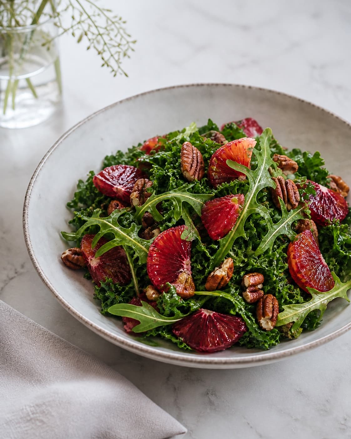 One serving bowl of green arugula-kale salad with distinct ruby blood-orange segments and coarsely chopped pecans, no extra bowls plates or whole oranges under tilberedningen af blodappelsinsalat med rucola