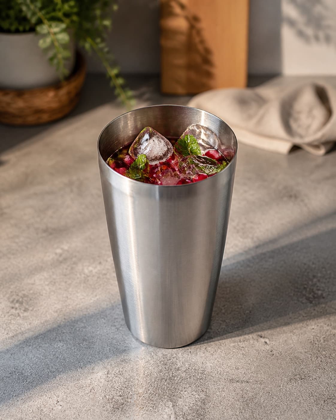 One open cocktail shaker containing ruby pomegranate-mint mixture, clear aquavit and ice cubes, no soda glasses garnish or bottles under tilberedningen af nytårscocktail med granatæble og snaps