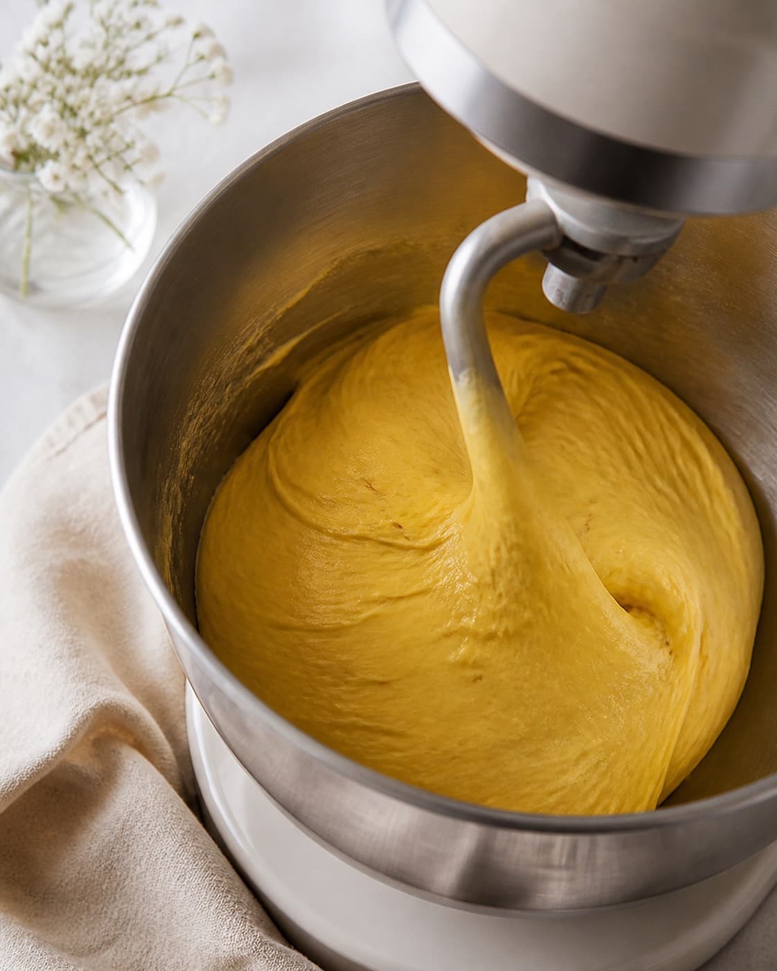 One stand-mixer bowl holding smooth golden-yellow slightly sticky saffron dough, no filling cream icing or baked buns under tilberedningen af safranboller med remonce