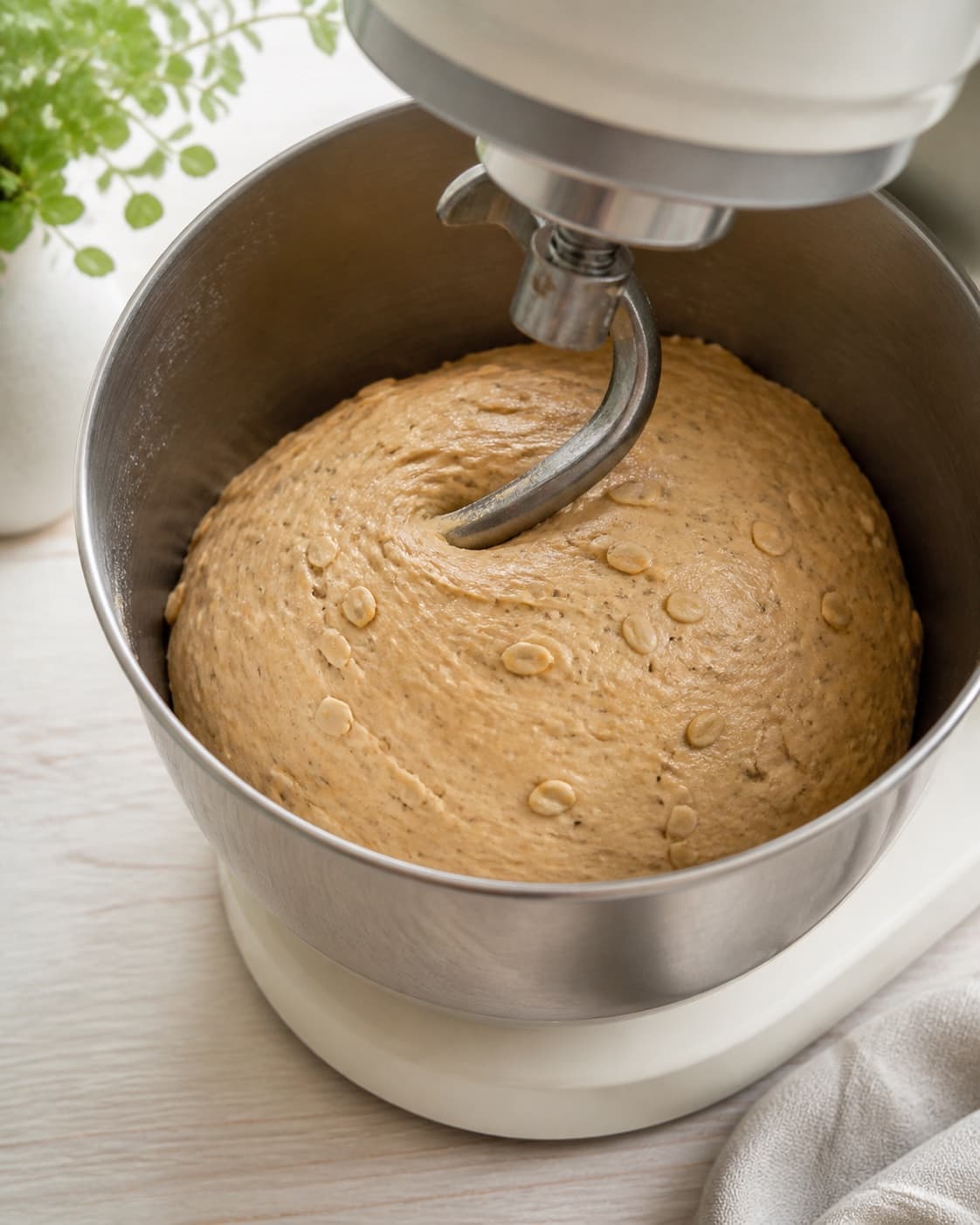 One stand-mixer bowl holding smooth elastic light-brown dough evenly filled with seeds and kernels, no shaped buns or trays under tilberedningen af kerneboller