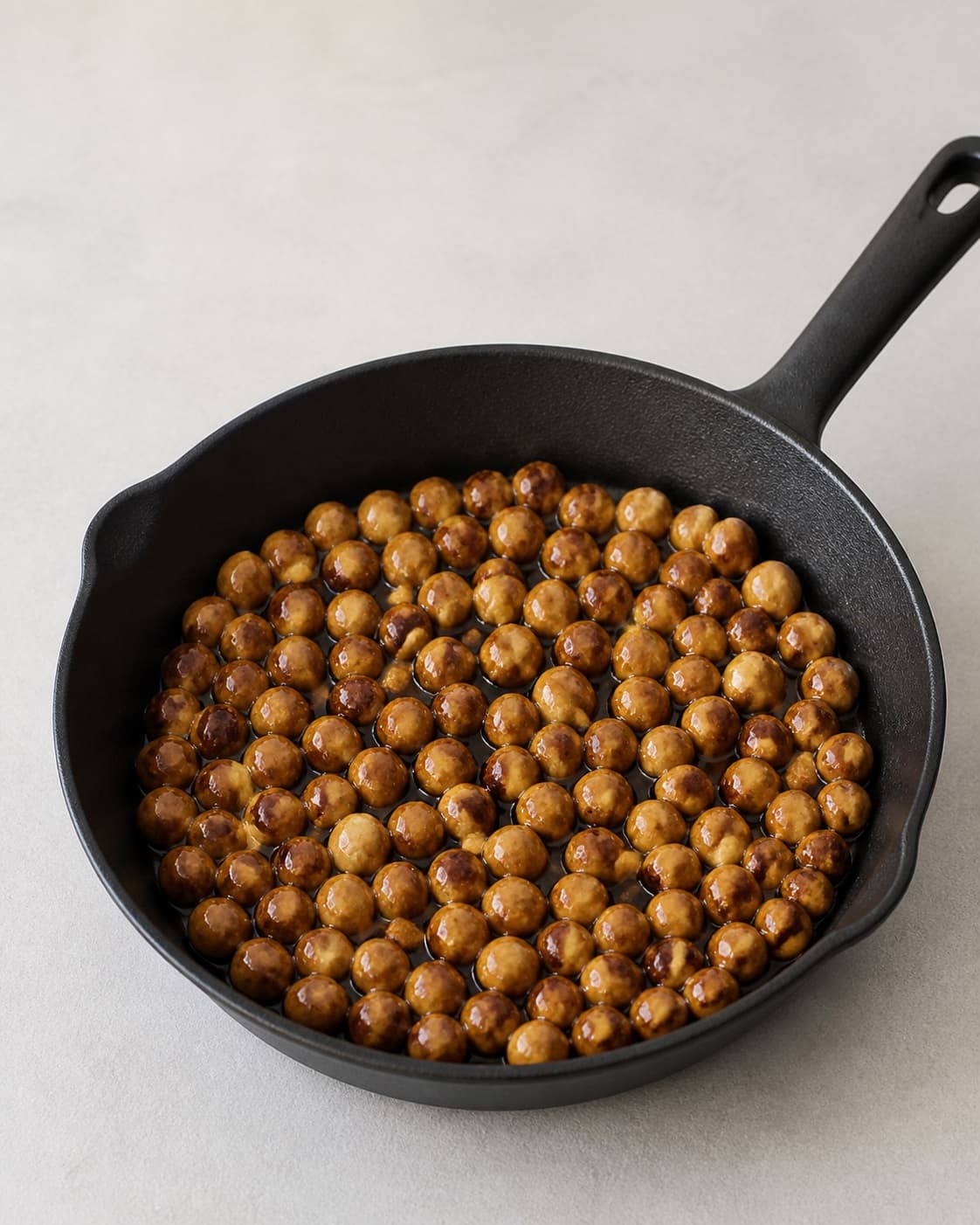 One skillet of whole hazelnuts evenly coated in glossy light-golden caramel, no chocolate cream jars or chopped nuts under tilberedningen af chokoladesmør med hasselnøddeknas