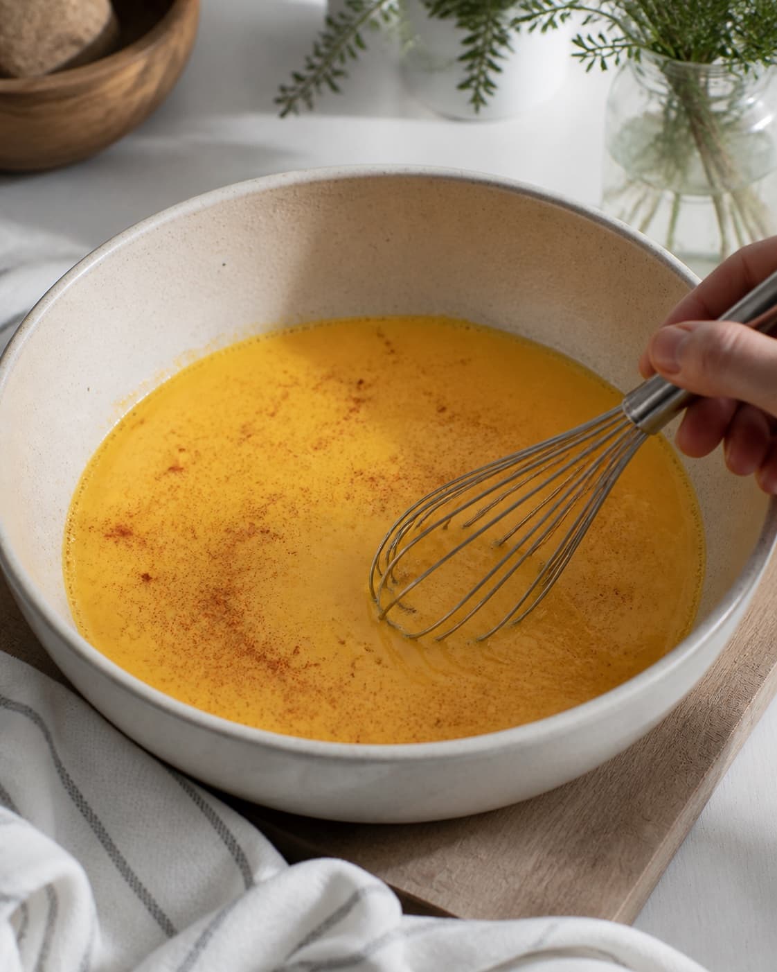 One large bowl of smooth orange-yellow egg and milk mixture flecked with paprika, no bread cheese chorizo or baking tin under tilberedningen af strata med æg og chorizo