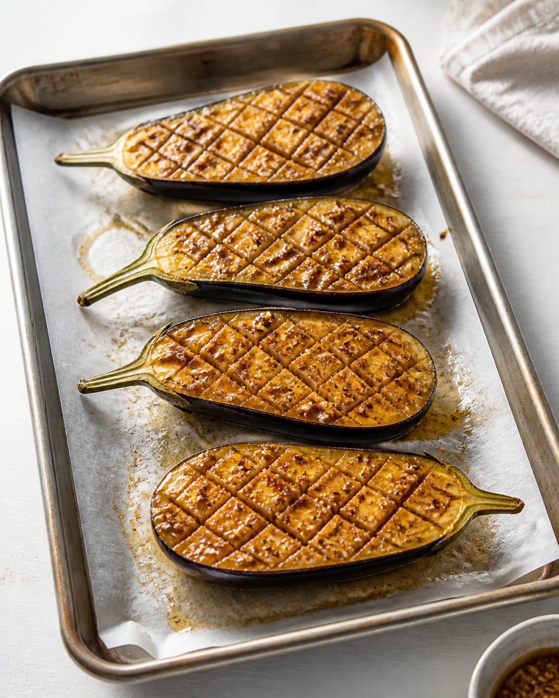 Four raw scored aubergine halves glossy with golden garlic cumin chilli marinade worked into every cut, no bulgur yogurt or toppings under tilberedningen af bagte auberginer med bulgur