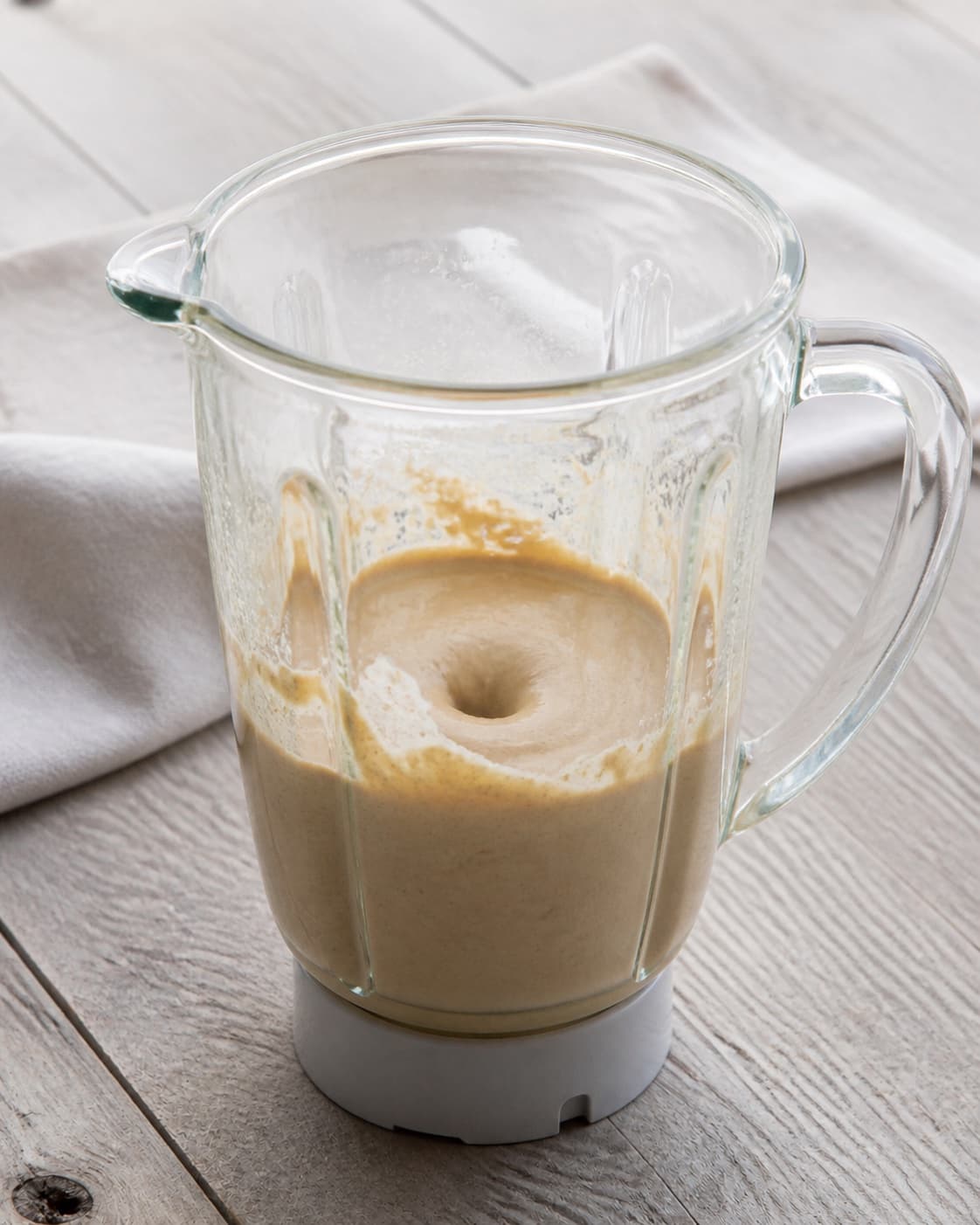 One blender jug holding thick smooth pale-brown sesame paste, no vegetables serving bowl or loose seeds under tilberedningen af goma dressing