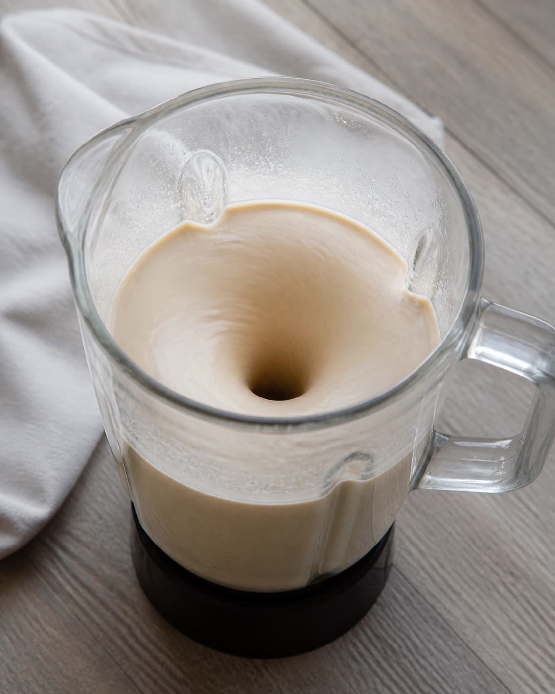 One blender jug holding silky smooth creamy goma dressing in a slow vortex, no vegetables bowl or garnish under tilberedningen af goma dressing