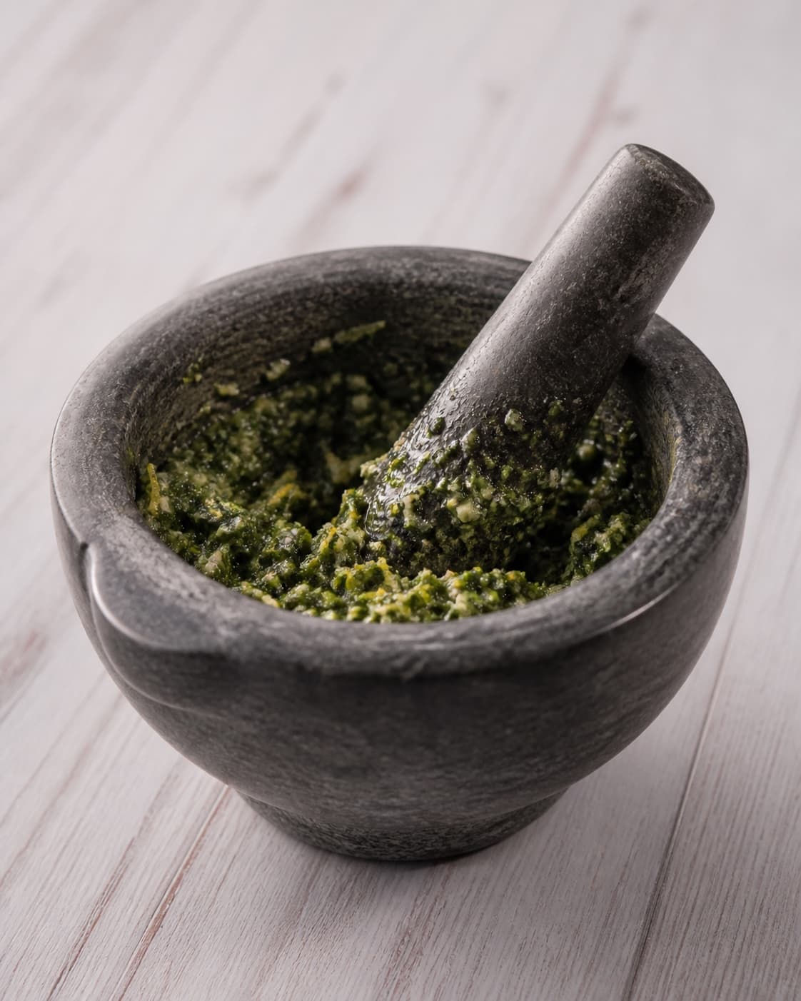 One mortar holding moist green herb and garlic paste flecked with lemon zest, no meat oven tray or extra ingredients under tilberedningen af lammeculotte