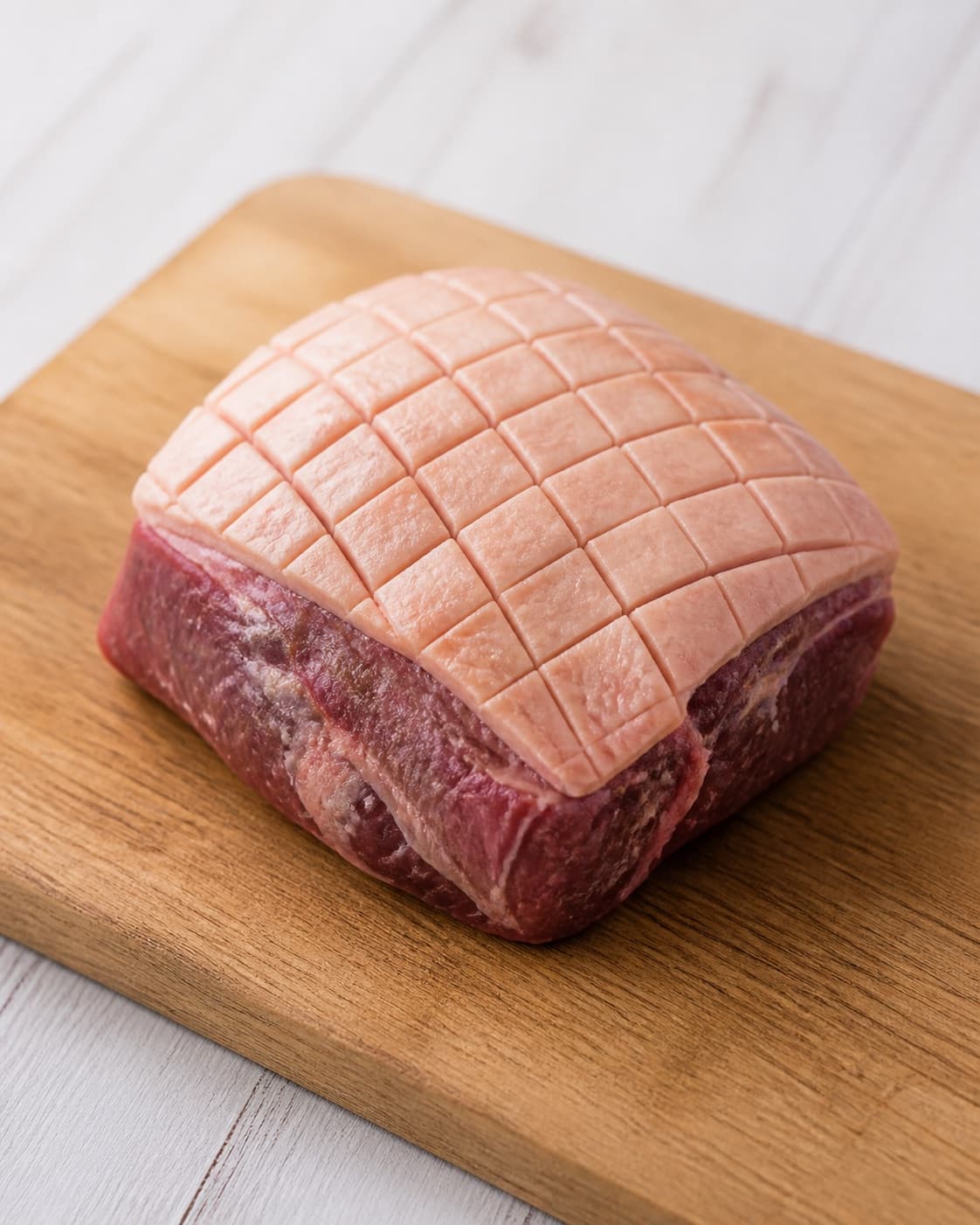 One raw lamb rump with dry fat cap precisely scored in a diamond pattern, no cuts into meat, no herbs or sides under tilberedningen af lammeculotte