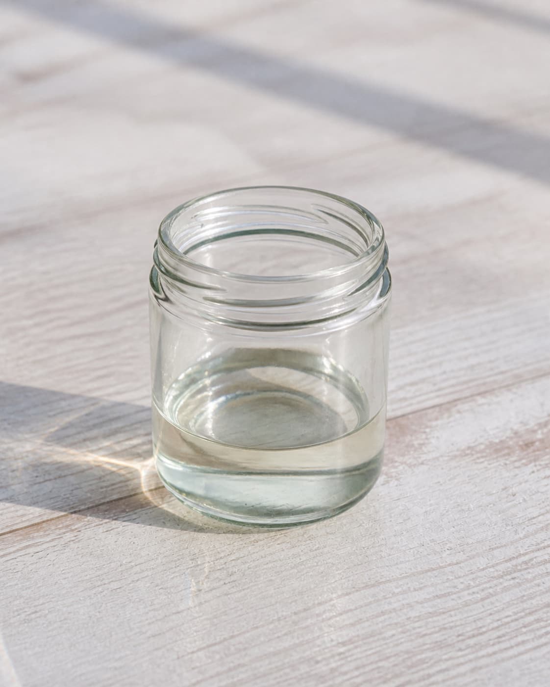 One small open glass jar containing clear cooled simple syrup, no lime cachaca ice cocktail glass or labels under tilberedningen af caipirinha cocktail