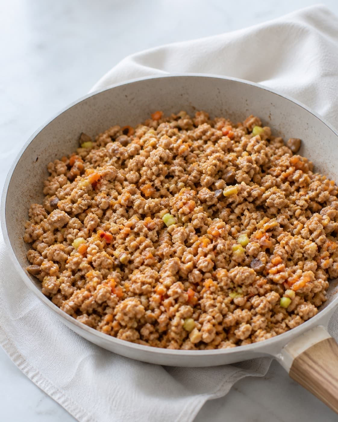 One skillet of fully cooked crumbly pork filling visibly mixed with carrot zucchini mushrooms and chilli, no raw pink meat wrappers or oil pot under tilberedningen af sprøde wontons