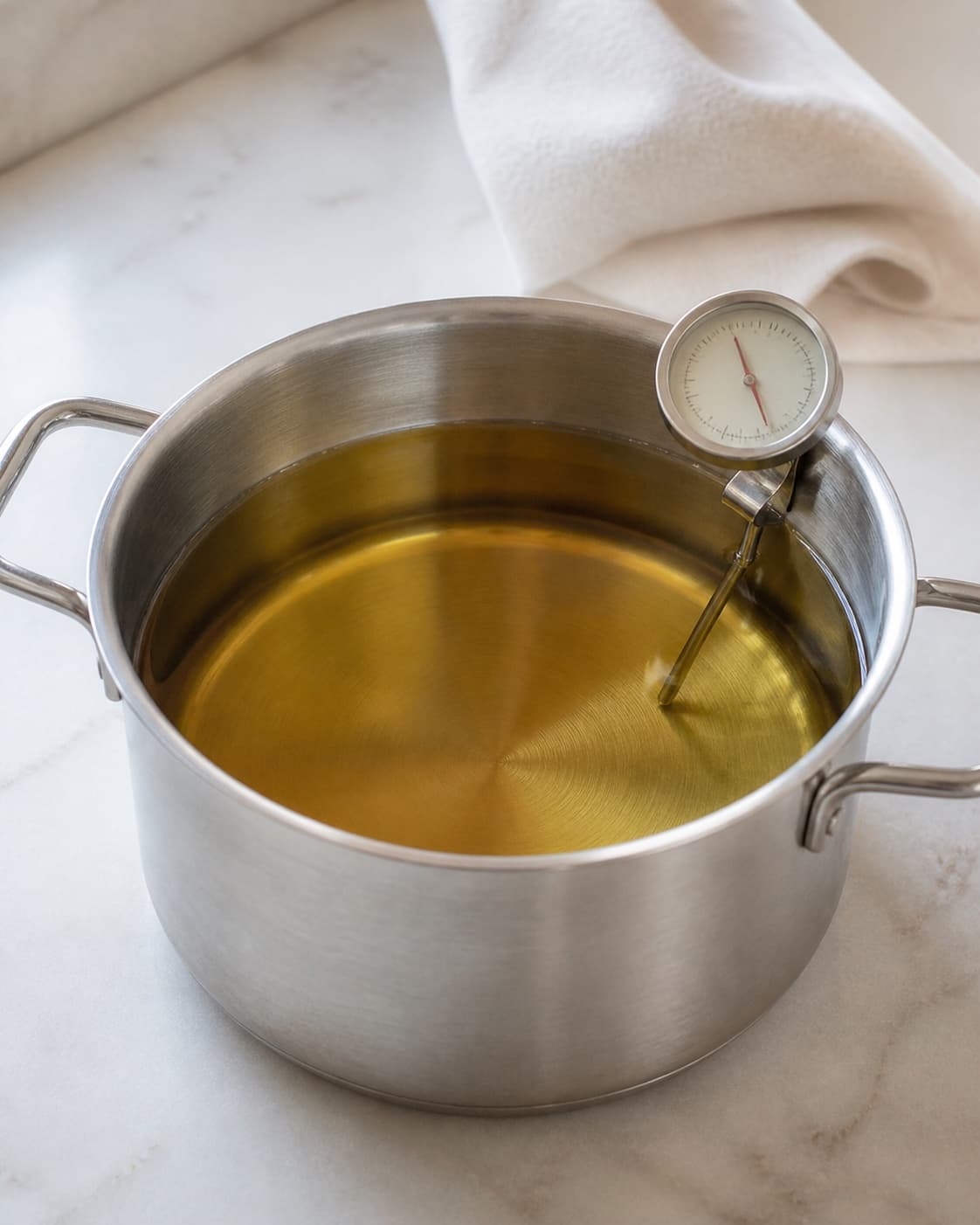 One stable deep pot of clear hot frying oil with a digital thermometer reading 175 degrees Celsius, no wontons food hands or flames under tilberedningen af sprøde wontons
