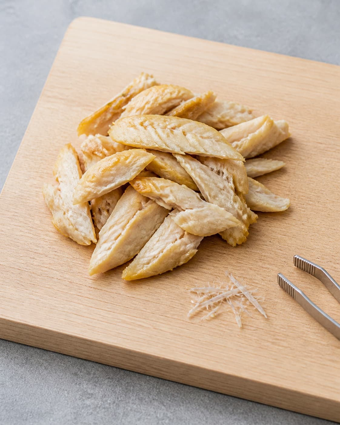 One cutting board holding cleaned smoked mackerel flakes with removed skin and a few bones placed separately, no dressing herbs bread or garnish under tilberedningen af makrelmousse - røget makrelrilette