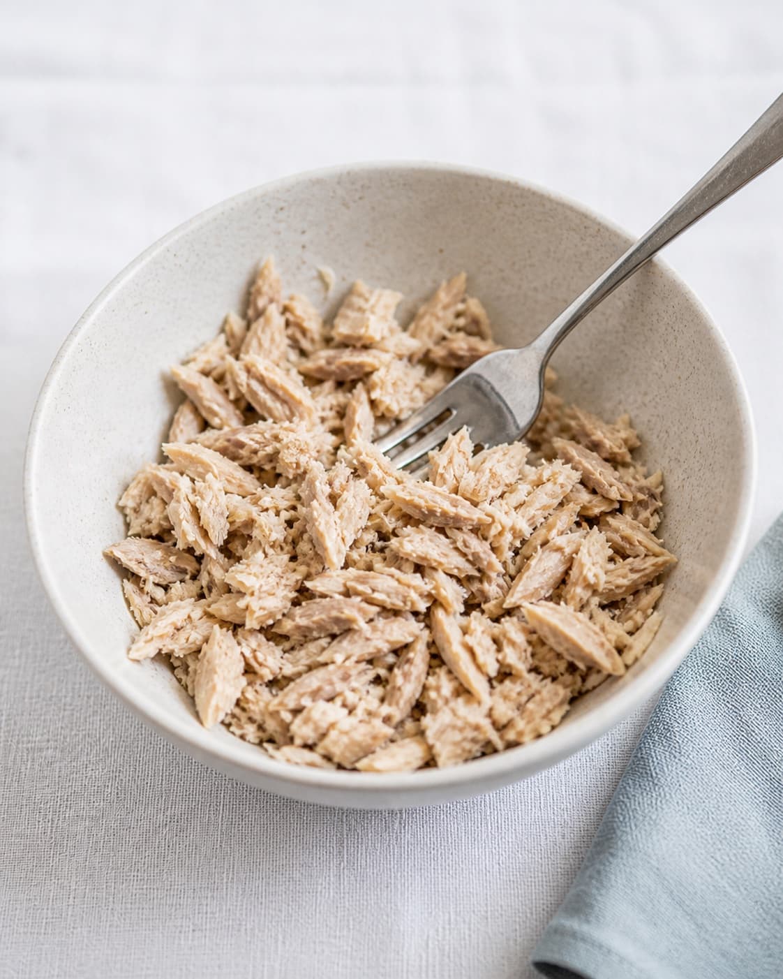 One bowl holding evenly flaked smoked mackerel and one fork, no creme fraiche mayonnaise lemon chives bread or garnish under tilberedningen af makrelmousse - røget makrelrilette