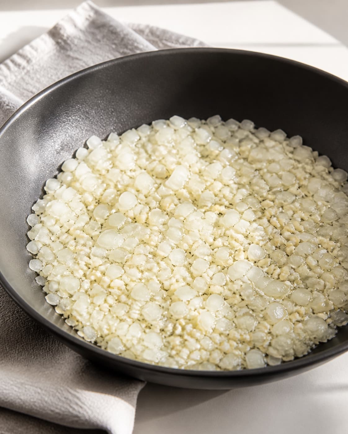 One large skillet holding soft glossy finely chopped onion and garlic, no rice dates spices nuts herbs or extra food under tilberedningen af indiske ris