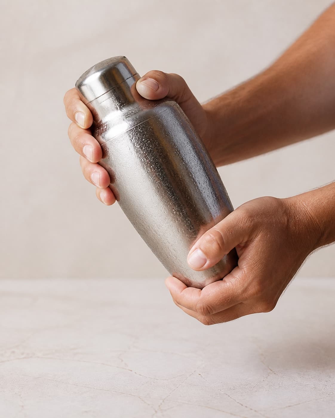 One closed stainless cocktail shaker covered in condensation being actively shaken, no glasses mint sparkling water garnish bottles or extra equipment under tilberedningen af ananasmojito med ingefær og mynte