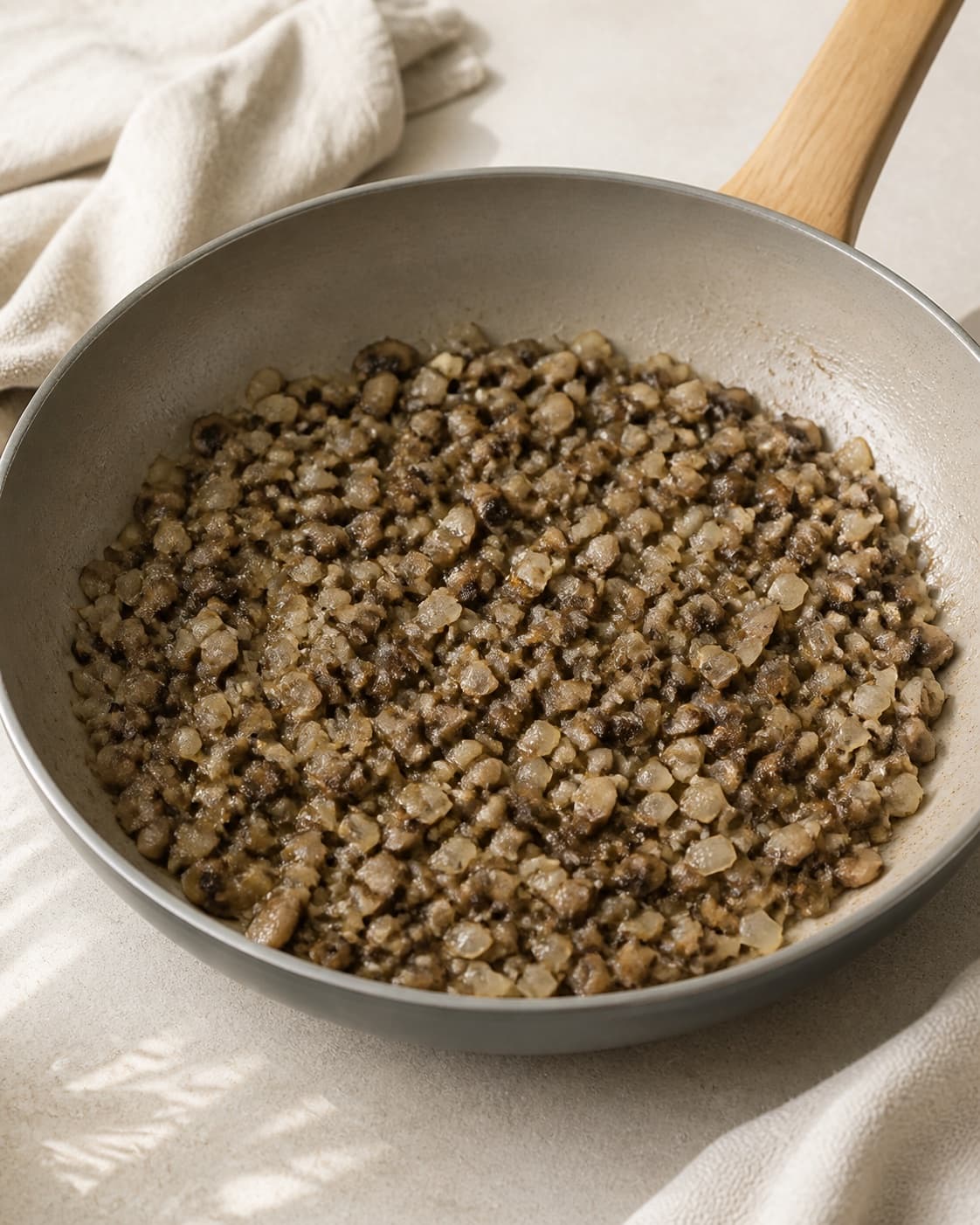One large skillet holding softened onion, minced garlic and browned finely chopped mushrooms with moisture cooked away, no meat carrot noodles wrappers herbs or extra food under tilberedningen af sprøde forårsruller
