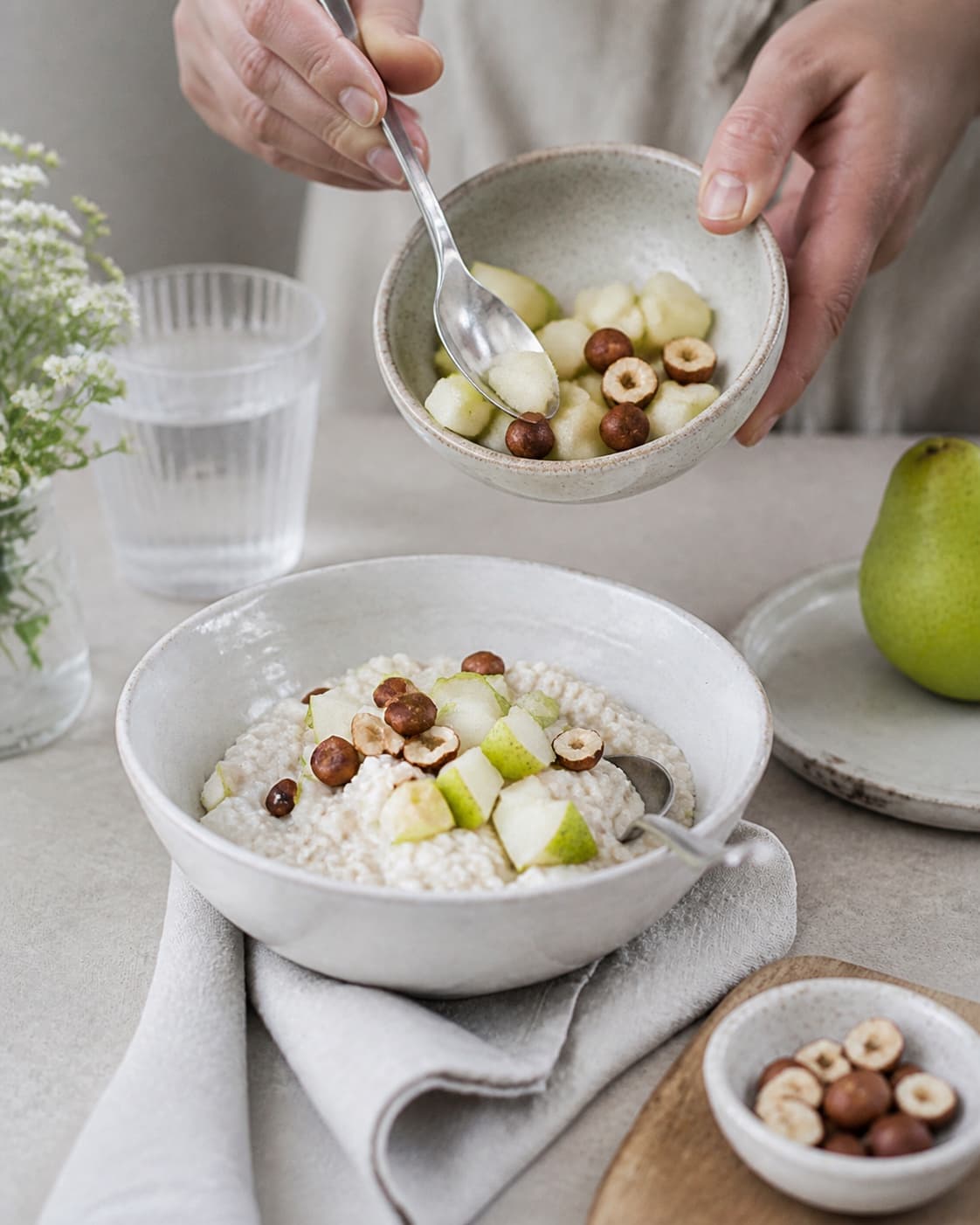 One single photorealistic instructional frame of finished breakfast bowls topped with the named fruit and garnish for Bircher Müsli med pære, featuring grove havregryn, pære, æblejuice, with only the named equipment and no unrelated food, text, logos or packaging under tilberedningen af bircher müsli med pære