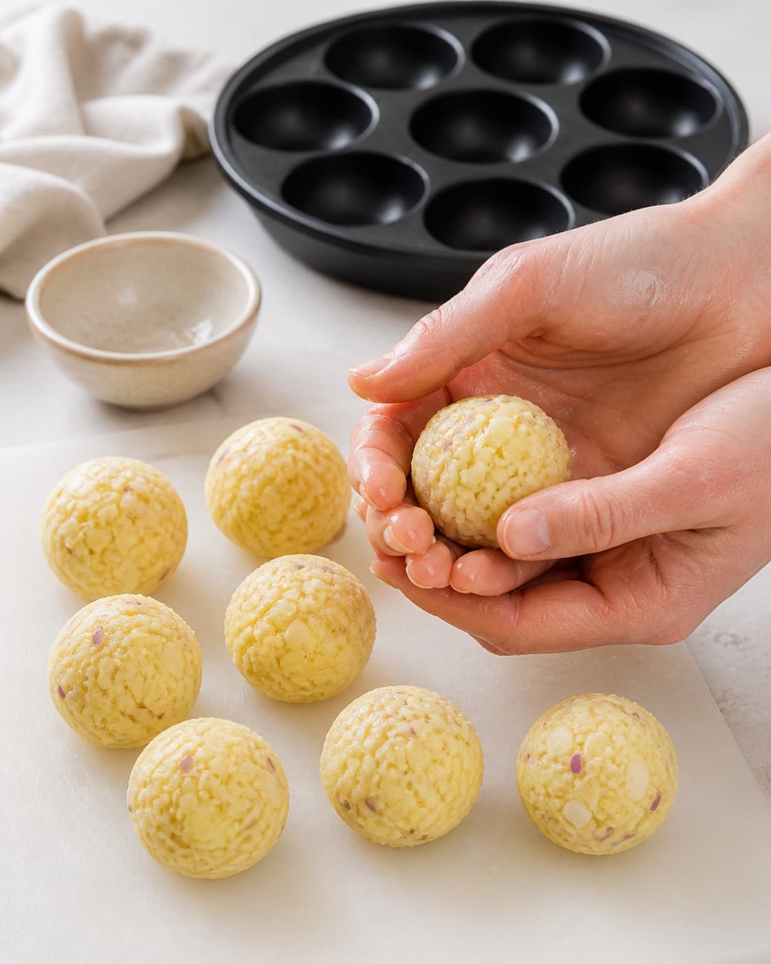 One single photorealistic instructional frame of realistic hands shaping equal raw patties on one board for Rösti - lavet i æbleskivepanden, featuring kartofler, løg, æg, with only the named equipment and no unrelated food, text, logos or packaging under tilberedningen af rösti - lavet i æbleskivepanden