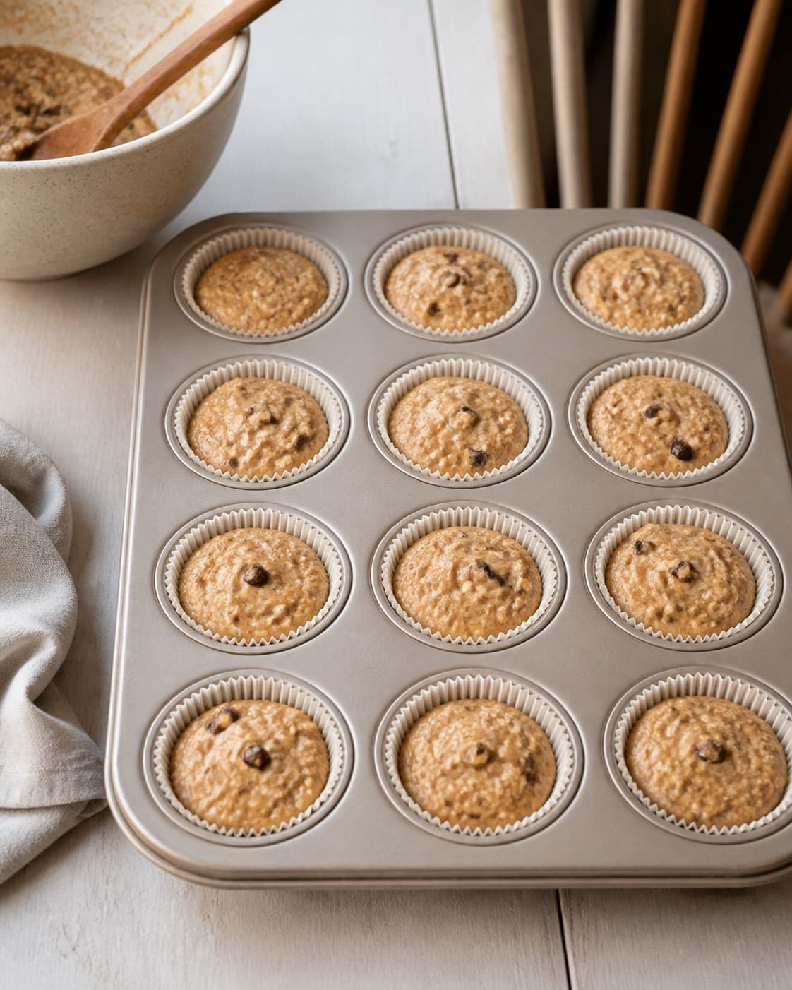 One single photorealistic instructional frame of equal muffin batter portions in one clean tray for Hverdagsmuffins uden sukker, featuring bananer, havregryn, æg, with only the named equipment and no unrelated food, text, logos or packaging under tilberedningen af hverdagsmuffins uden sukker