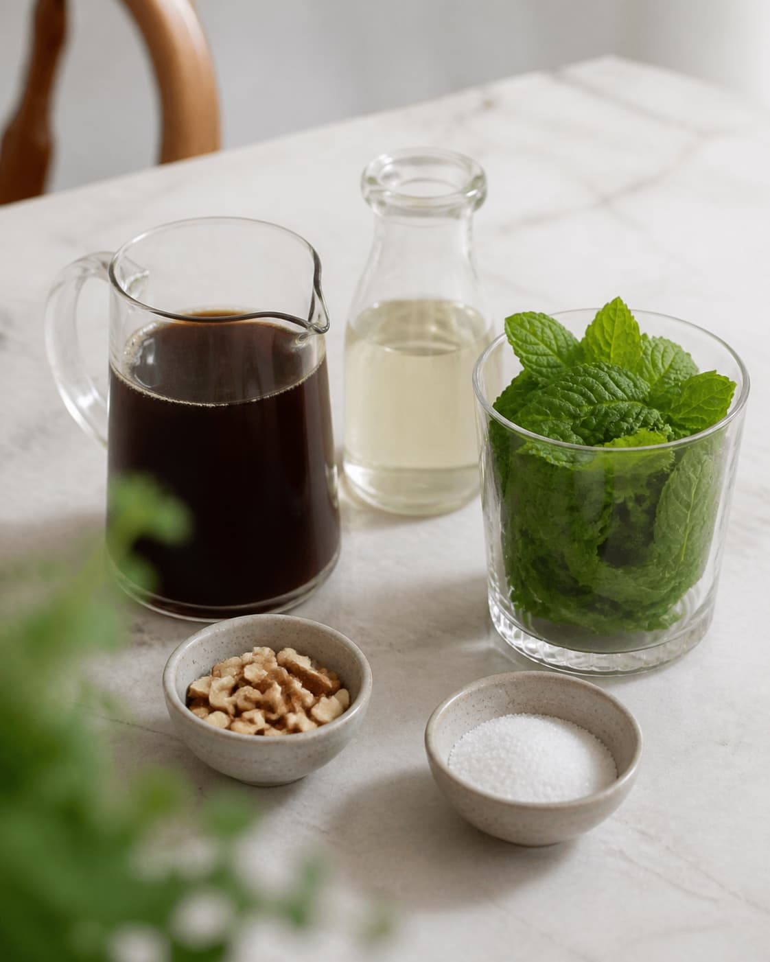 One single photorealistic instructional frame of measured drink components arranged separately for Iskaffe - med myntesirup og mandler, featuring stærk kaffe, frisk mynte, sukker, with only the named equipment and no unrelated food, text, logos or packaging under tilberedningen af iskaffe - med myntesirup og mandler