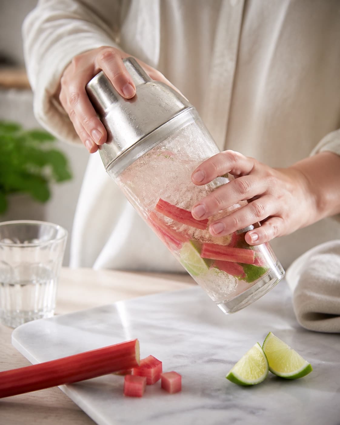 One single photorealistic instructional frame of the drink being shaken or stirred with clear ice for Rabarber Mojito, featuring rabarber, hvid rom, lime, with only the named equipment and no unrelated food, text, logos or packaging under tilberedningen af rabarber mojito