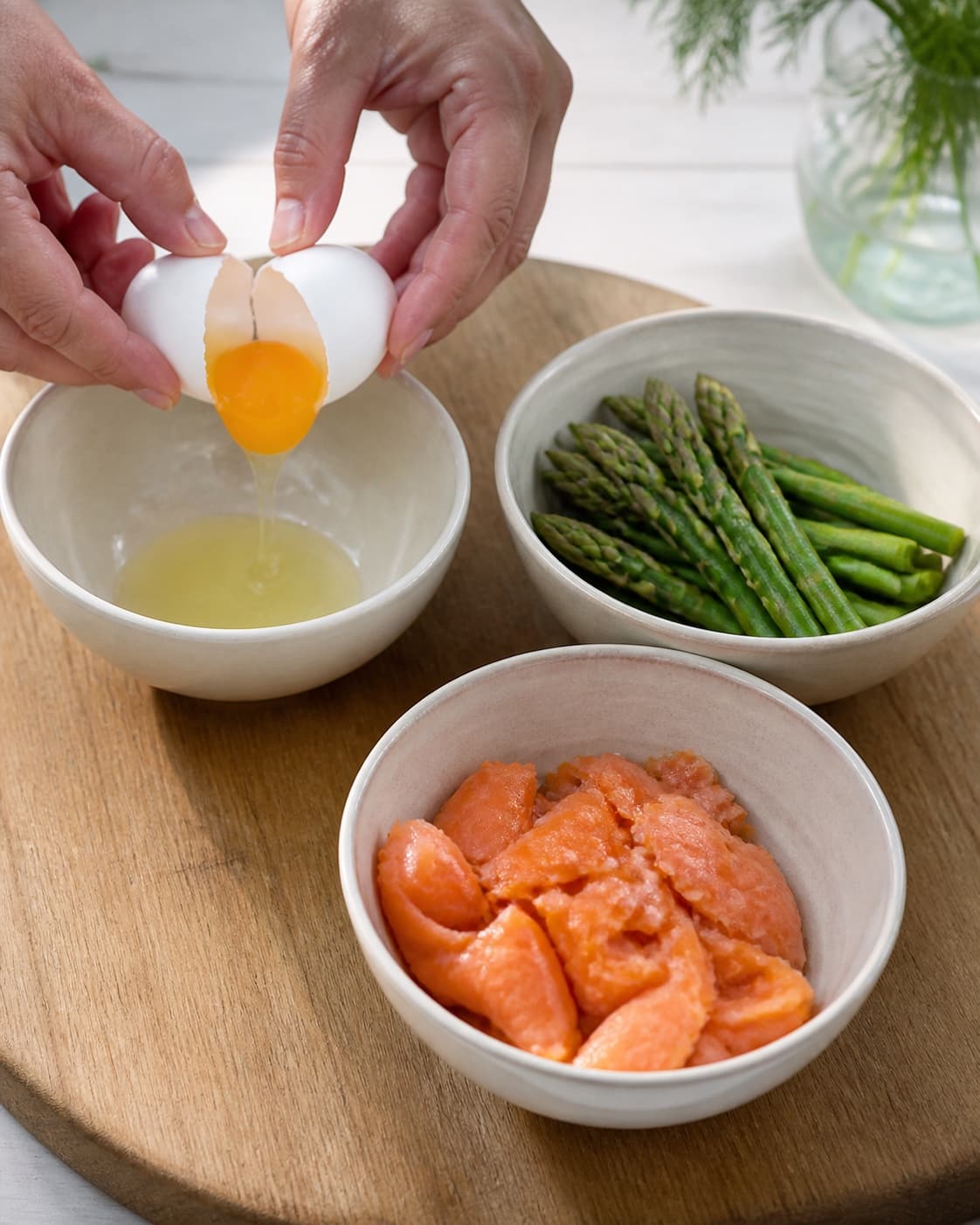 One single photorealistic instructional frame of prepared egg-dish fillings in separate bowls for Æg bagt med laks og asparges, featuring æg, varmrøget laks, grønne asparges, with only the named equipment and no unrelated food, text, logos or packaging under tilberedningen af æg bagt med laks og asparges