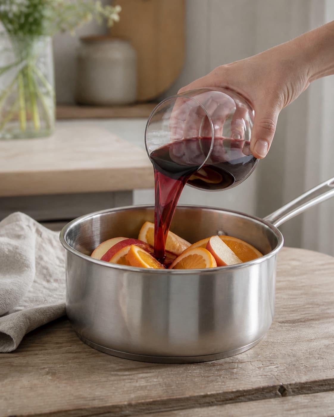 One single photorealistic instructional frame of the aromatic drink base being prepared in one small saucepan for Sangria, featuring rødvin, appelsin, æble, with only the named equipment and no unrelated food, text, logos or packaging under tilberedningen af sangria