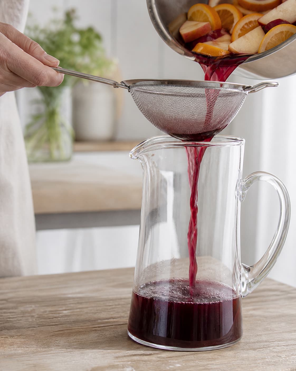 One single photorealistic instructional frame of a strained drink base cooling in one clear jug for Sangria, featuring rødvin, appelsin, æble, with only the named equipment and no unrelated food, text, logos or packaging under tilberedningen af sangria