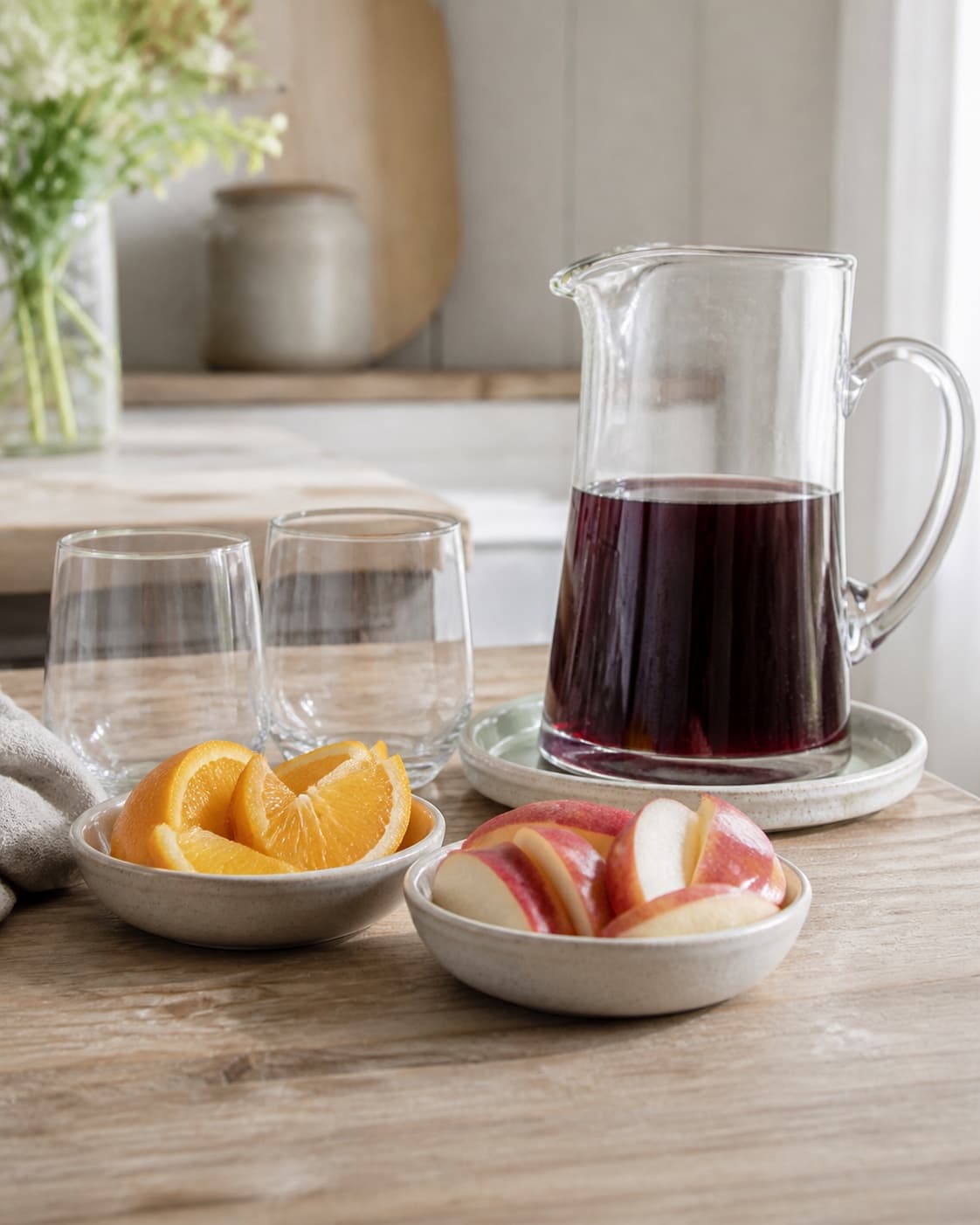 One single photorealistic instructional frame of measured drink components arranged separately for Sangria, featuring rødvin, appelsin, æble, with only the named equipment and no unrelated food, text, logos or packaging under tilberedningen af sangria