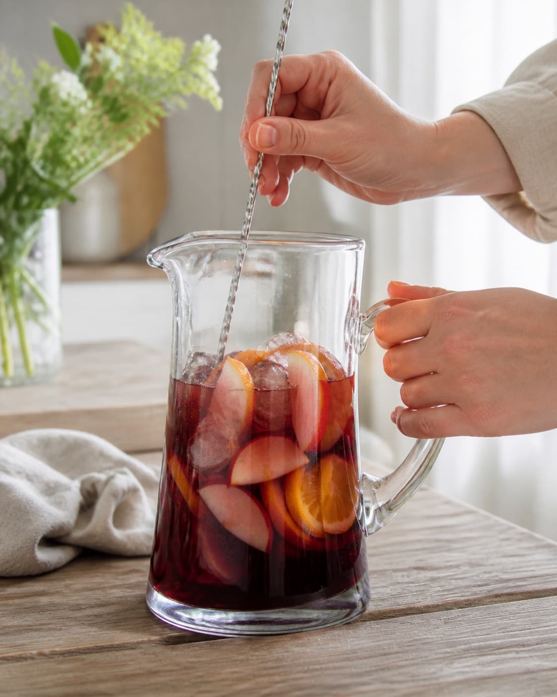 One single photorealistic instructional frame of the drink being shaken or stirred with clear ice for Sangria, featuring rødvin, appelsin, æble, with only the named equipment and no unrelated food, text, logos or packaging under tilberedningen af sangria
