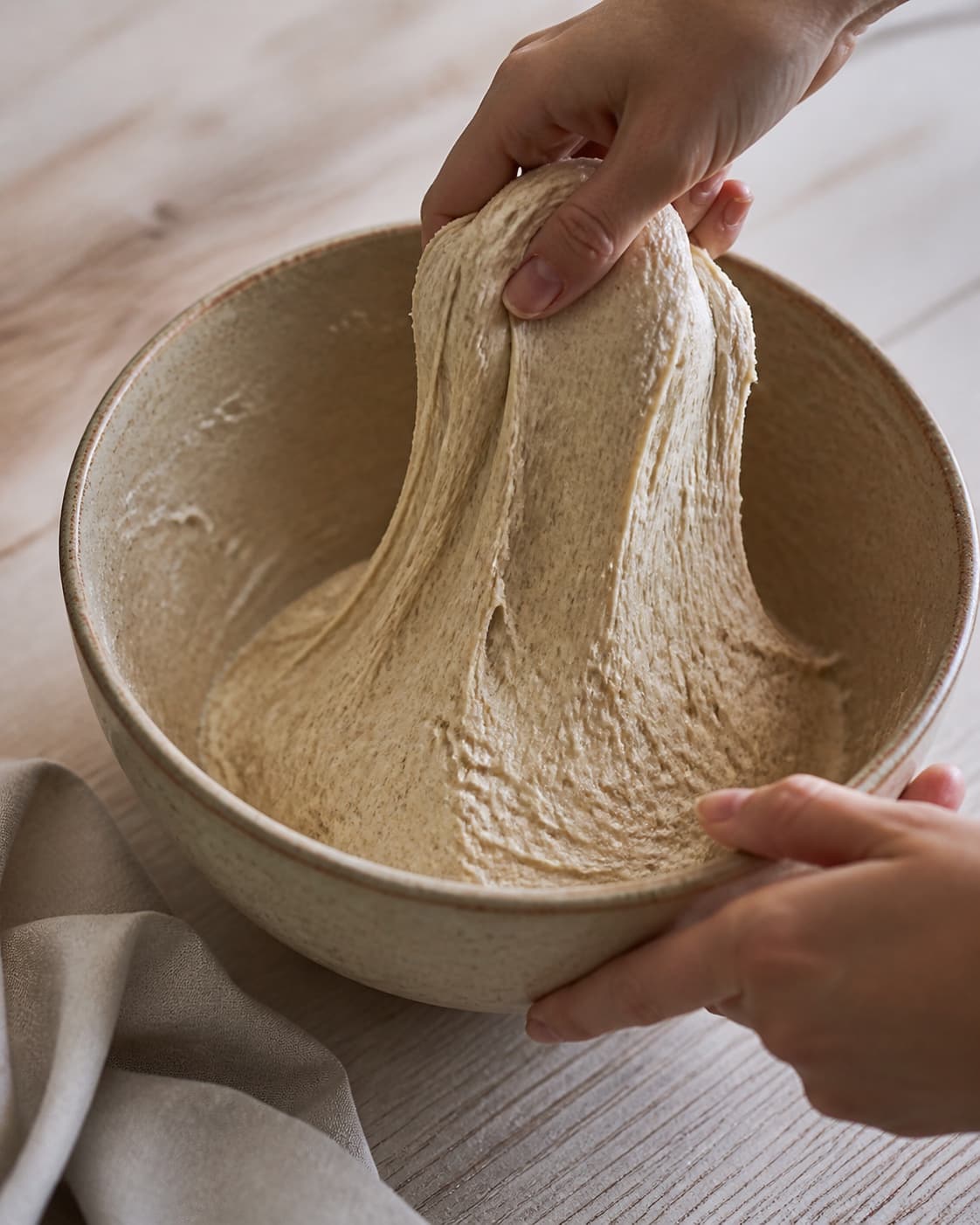 One single photorealistic instructional frame of elastic pizza dough mixing in one bowl for Rugpizza med jordskokker, timian og æg, featuring rugmel, hvedemel, gær, with only the named equipment and no unrelated food, text, logos or packaging under tilberedningen af rugpizza med jordskokker, timian og æg