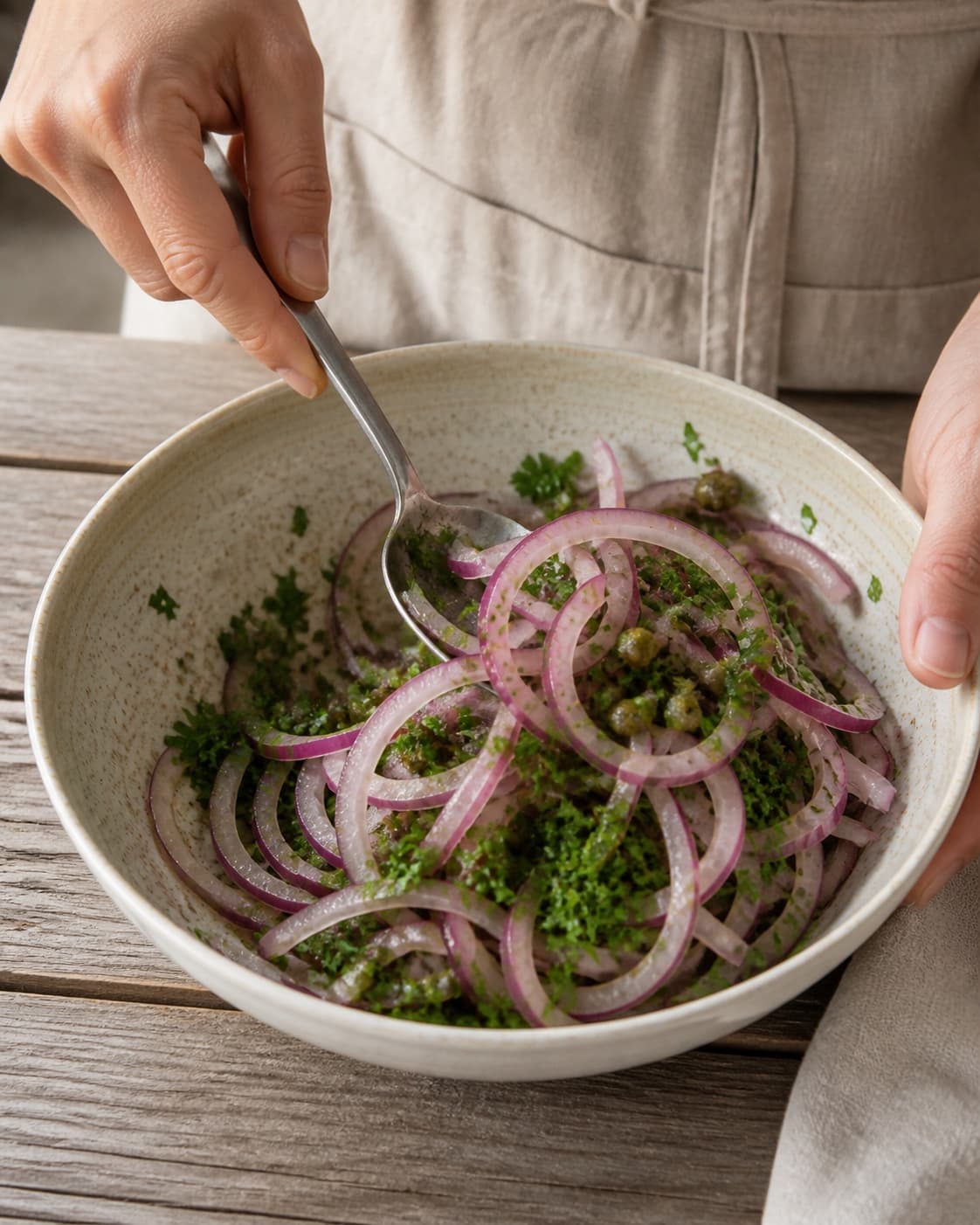 One single photorealistic instructional frame of the prepared salad components being gently tossed together for Løgsalat, featuring rødløg, bredbladet persille, kapers, with only the named equipment and no unrelated food, text, logos or packaging under tilberedningen af løgsalat