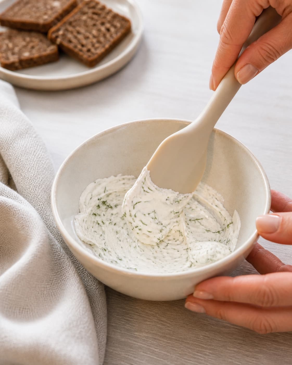 One single photorealistic instructional frame of a smooth savory spread in one small bowl for 3 nemme hapsere, featuring rugbrød, varmrøget laks, flødeost, with only the named equipment and no unrelated food, text, logos or packaging under tilberedningen af 3 nemme hapsere