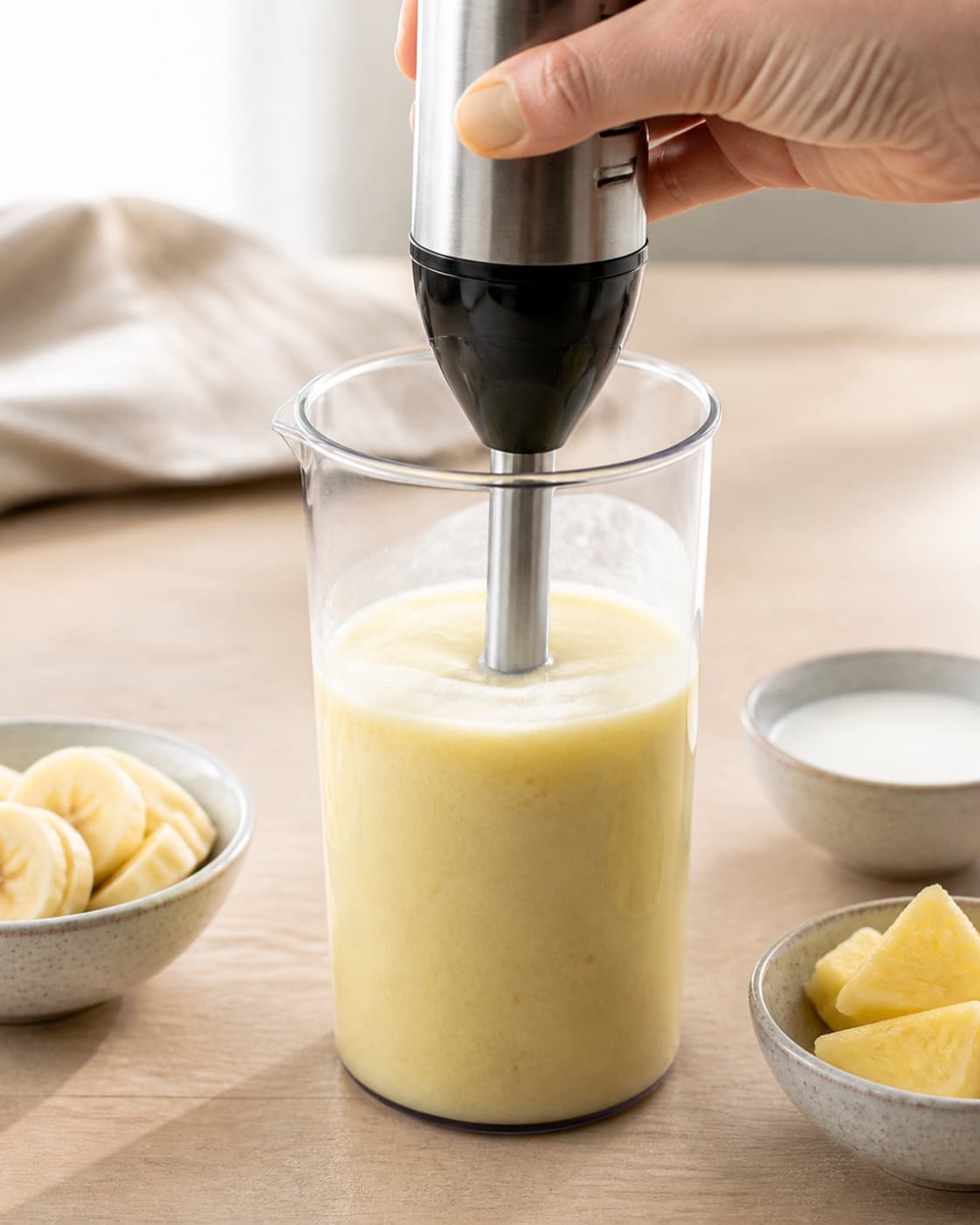 One single photorealistic instructional frame of the final colorful smoothie blending until thick and uniform for Pina Colada Smoothie - uden alkohol, featuring ananas, kokosmælk, banan, with only the named equipment and no unrelated food, text, logos or packaging under tilberedningen af pina colada smoothie - uden alkohol