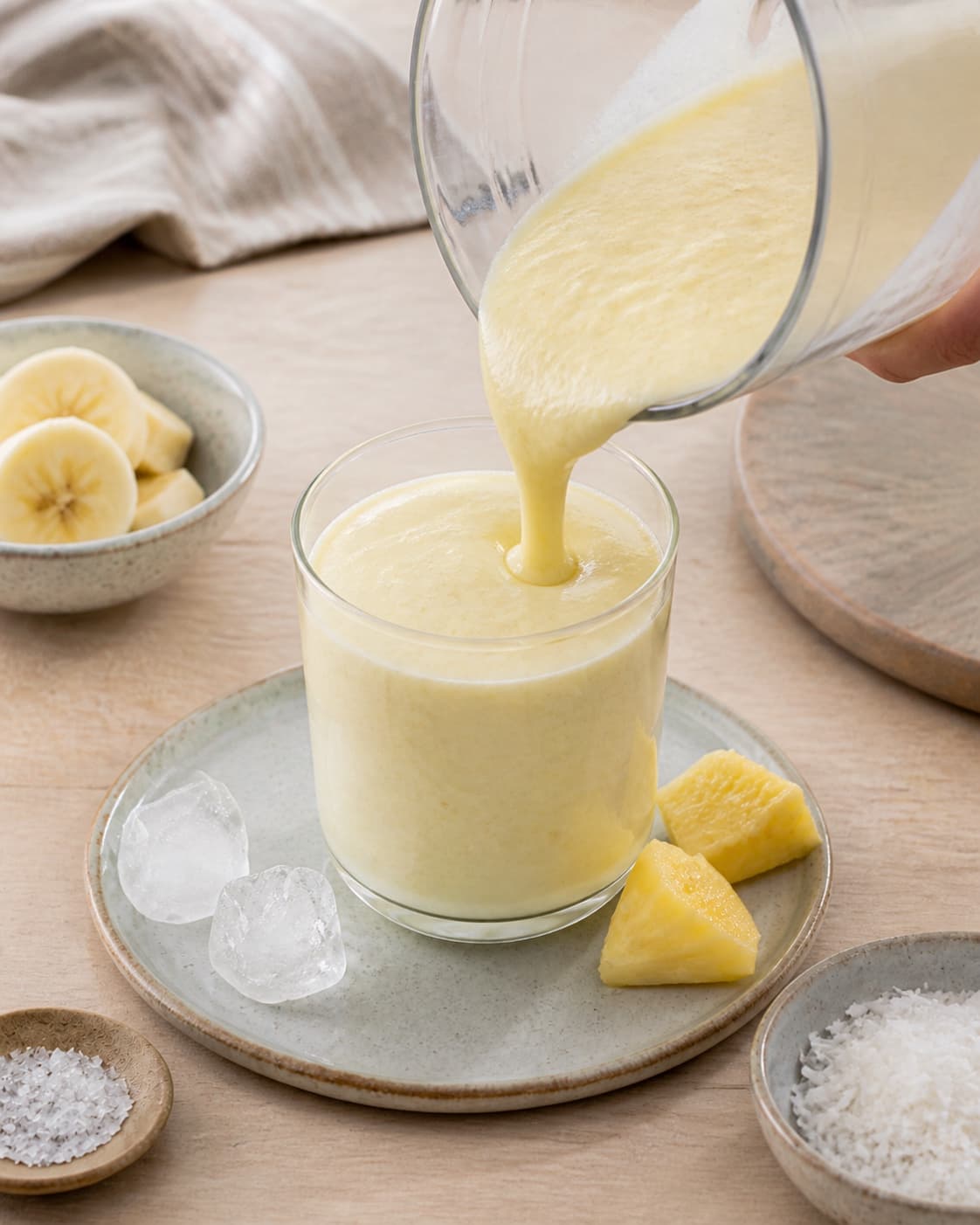 One single photorealistic instructional frame of the finished smoothie poured into clean chilled glasses or bowls for Pina Colada Smoothie - uden alkohol, featuring ananas, kokosmælk, banan, with only the named equipment and no unrelated food, text, logos or packaging under tilberedningen af pina colada smoothie - uden alkohol