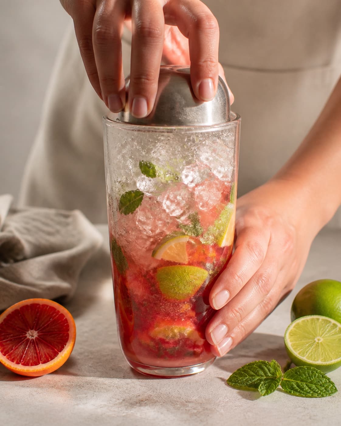 One single photorealistic instructional frame of the drink being shaken or stirred with clear ice for Blodappelsin Mojito, featuring hvid rom, blodappelsiner, lime, with only the named equipment and no unrelated food, text, logos or packaging under tilberedningen af blodappelsin mojito