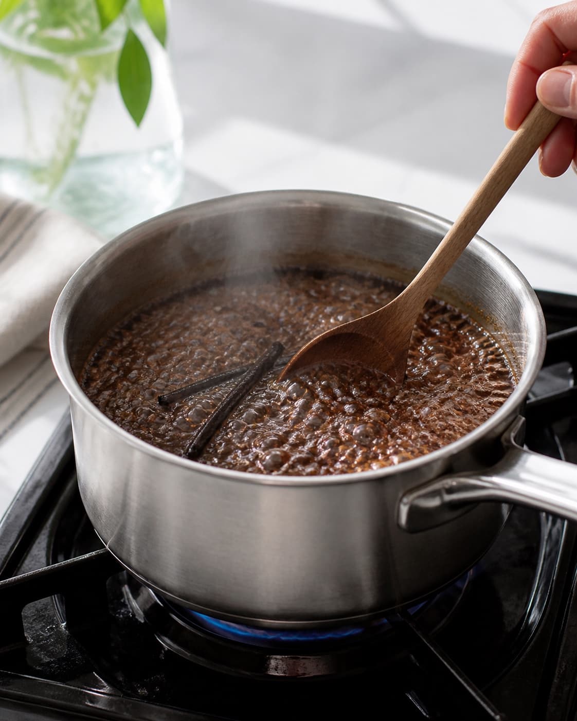 One single photorealistic instructional frame of the sauce base simmering in one saucepan for Kaffesirup, featuring stærk kaffe, sukker, vaniljestang, with only the named equipment and no unrelated food, text, logos or packaging under tilberedningen af kaffesirup