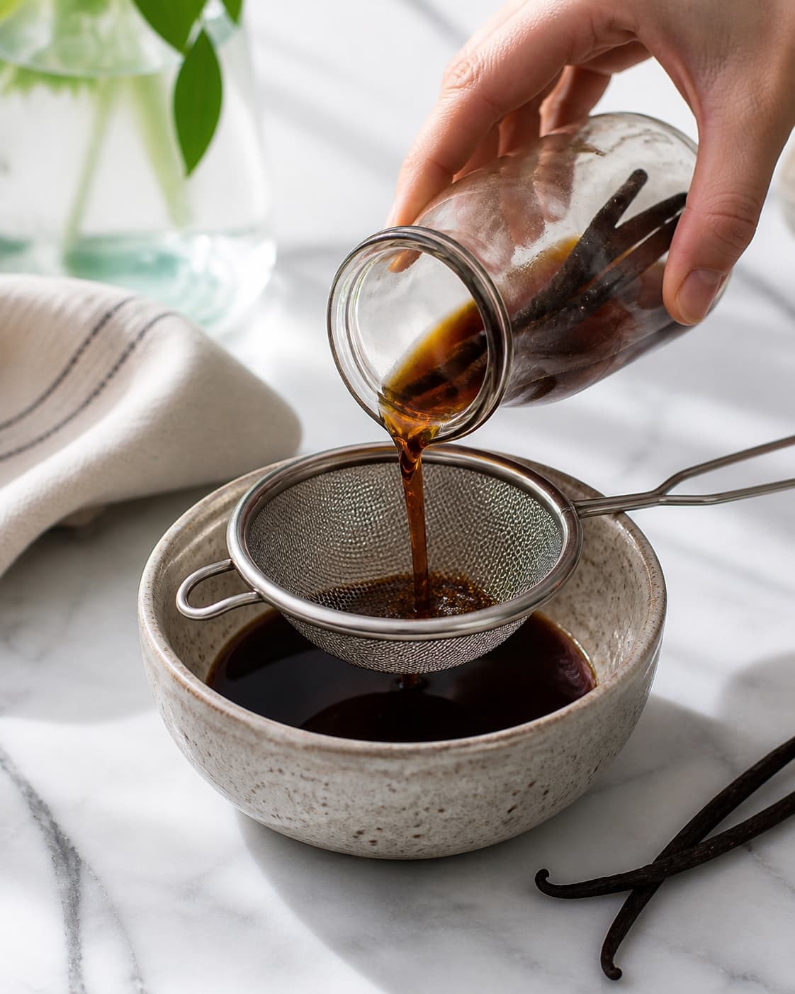 One single photorealistic instructional frame of the cooked sauce being blended or strained smooth for Kaffesirup, featuring stærk kaffe, sukker, vaniljestang, with only the named equipment and no unrelated food, text, logos or packaging under tilberedningen af kaffesirup