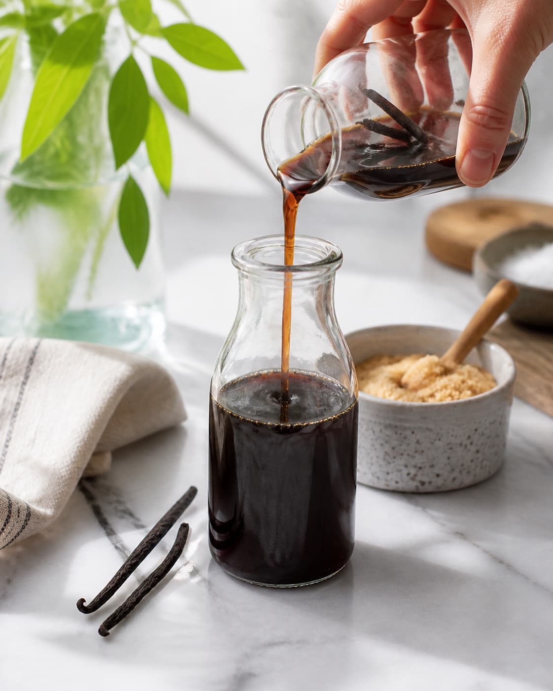 One single photorealistic instructional frame of the finished sauce being transferred into one clean jar for Kaffesirup, featuring stærk kaffe, sukker, vaniljestang, with only the named equipment and no unrelated food, text, logos or packaging under tilberedningen af kaffesirup