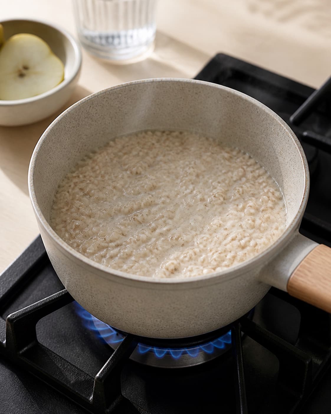 One single photorealistic instructional frame of creamy breakfast porridge gently simmering in one pot for Krydret morgengrød, featuring havregryn, mælk, pære, with only the named equipment and no unrelated food, text, logos or packaging under tilberedningen af krydret morgengrød