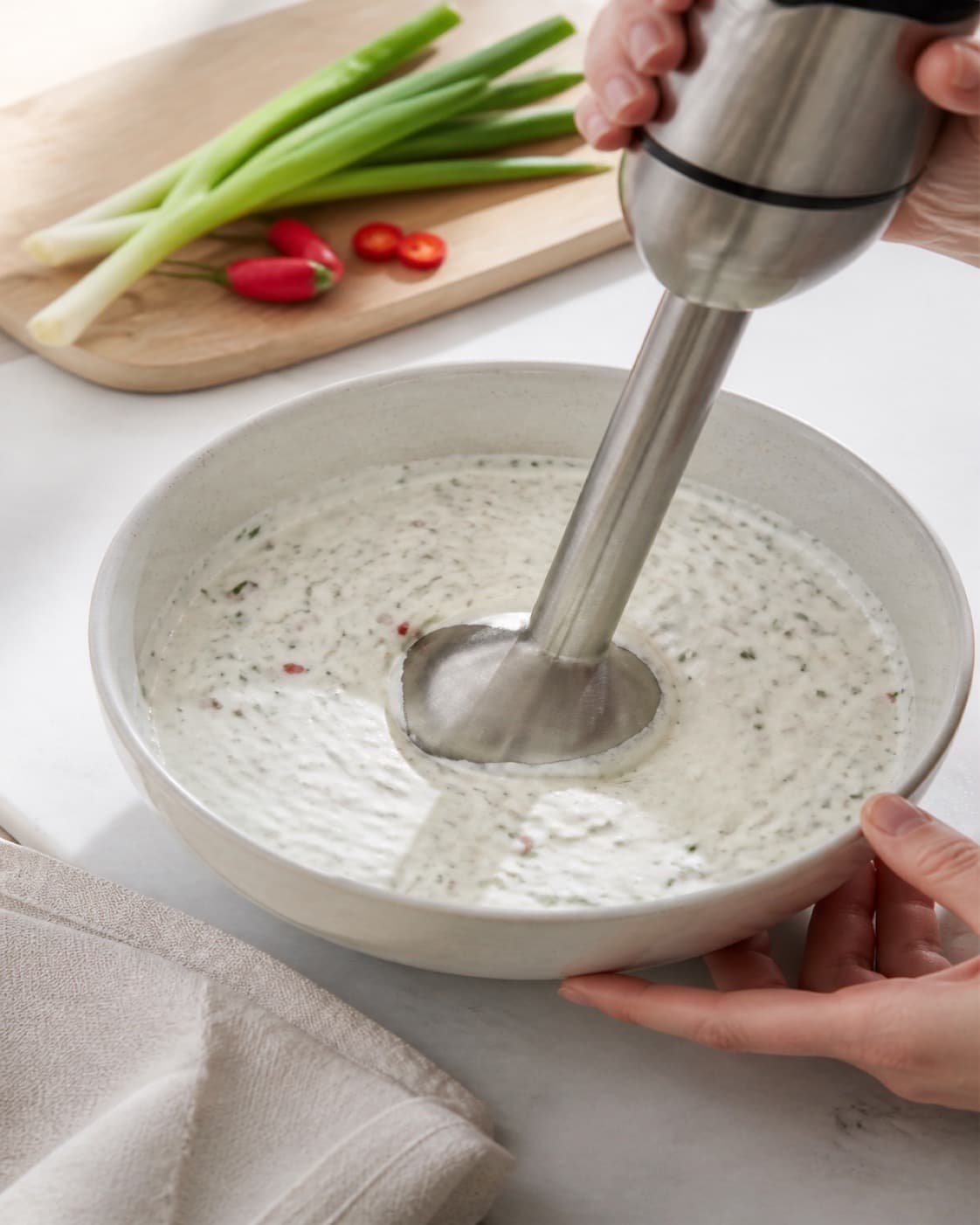 One single photorealistic instructional frame of the dip blending into a smooth cohesive texture for 3 x hjemmelavet dip til chips, featuring cremefraiche 18 %, forårsløg, rød chili, with only the named equipment and no unrelated food, text, logos or packaging under tilberedningen af 3 x hjemmelavet dip til chips