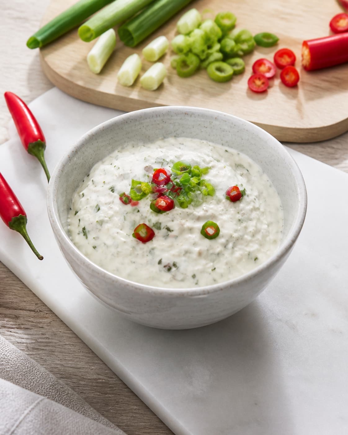 One single photorealistic instructional frame of the completed dip in one clean bowl after chilling for 3 x hjemmelavet dip til chips, featuring cremefraiche 18 %, forårsløg, rød chili, with only the named equipment and no unrelated food, text, logos or packaging under tilberedningen af 3 x hjemmelavet dip til chips