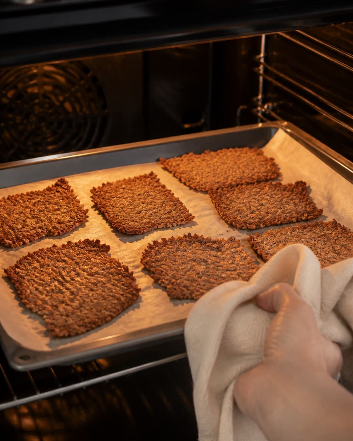 One single photorealistic instructional frame of the seasoned main ingredient roasting until properly cooked for Sprøde grødchips med dilddip, featuring kold havregrød, æg, havregryn, with only the named equipment and no unrelated food, text, logos or packaging under tilberedningen af sprøde grødchips med dilddip
