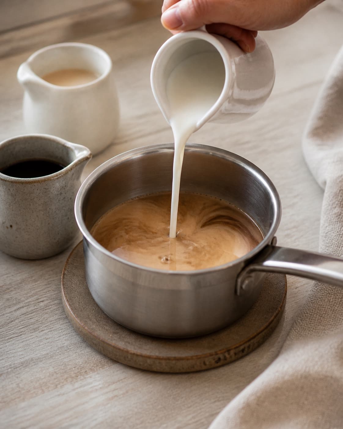 One single photorealistic instructional frame of the aromatic drink base being prepared in one small saucepan for Baileys med kaffe isterninger, featuring Baileys, stærk kaffe, mælk, with only the named equipment and no unrelated food, text, logos or packaging under tilberedningen af baileys med kaffe isterninger