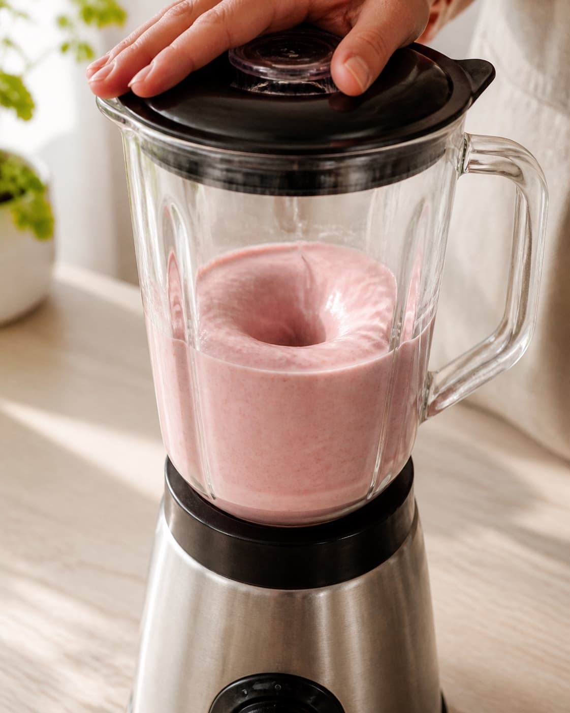 One single photorealistic instructional frame of a smooth pale base swirling inside one blender for Sommerlækker smoothieskål, featuring jordbær, fersken, banan, with only the named equipment and no unrelated food, text, logos or packaging under tilberedningen af sommerlækker smoothieskål