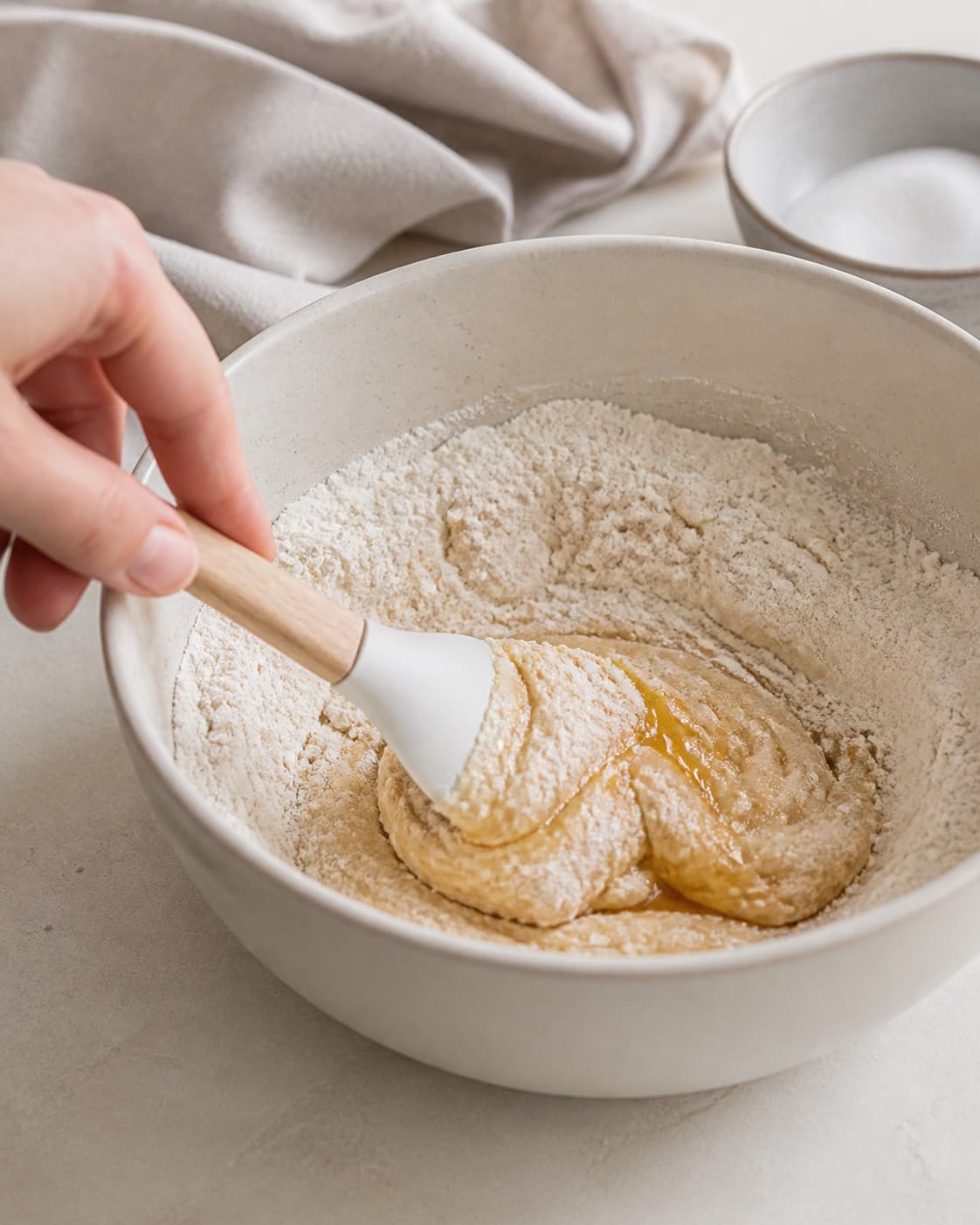 One single photorealistic instructional frame of the flavoring being folded into the confection mixture for Hjemmelavet twix, featuring hvedemel, smør, sukker, with only the named equipment and no unrelated food, text, logos or packaging under tilberedningen af hjemmelavet twix