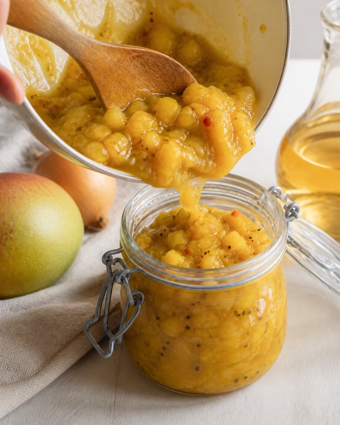 One single photorealistic instructional frame of the finished sauce being transferred into one clean jar for Mango Chutney, featuring mango, løg, æblecidereddike, with only the named equipment and no unrelated food, text, logos or packaging under tilberedningen af mango chutney