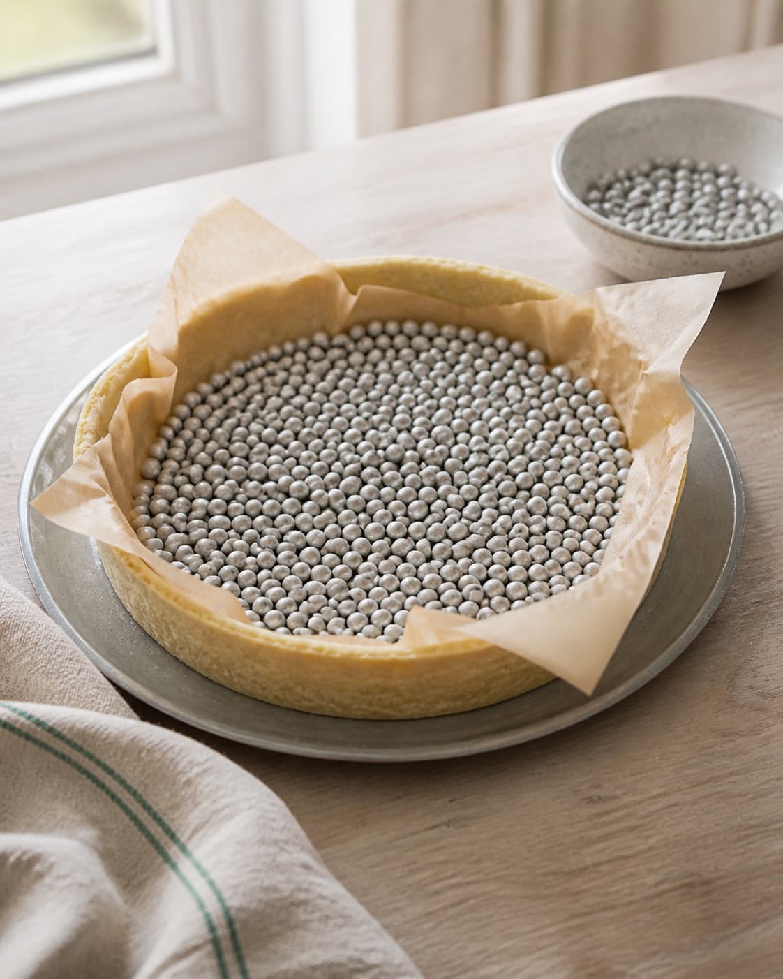 One round pastry shell being blind baked with parchment and baking weights, no spinach, salmon, rolled strudel or finished tart under tilberedningen af spinattærte med laks