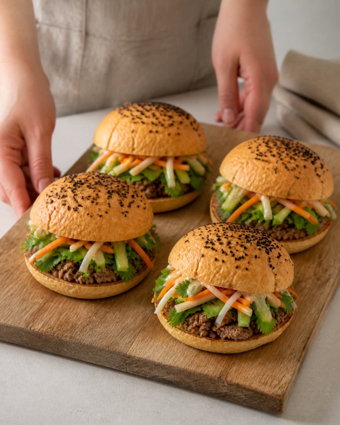 One single photorealistic instructional frame of four completed burgers assembled neatly on one board for Banh Mi Burger, featuring hakket svinekød, burgerboller, gulerødder, with only the named equipment and no unrelated food, text, logos or packaging under tilberedningen af banh mi burger