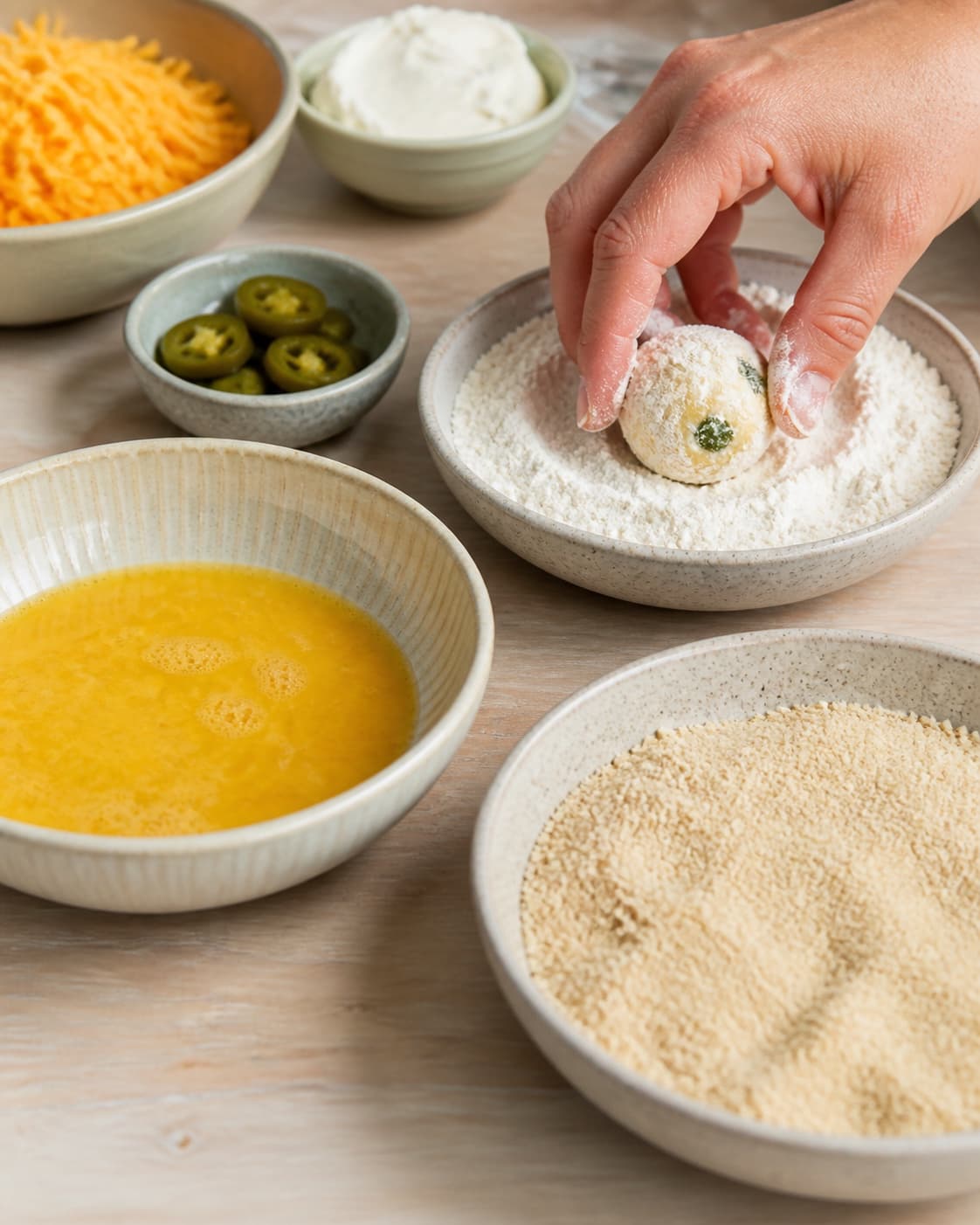 One single photorealistic instructional frame of a clear breading station with flour egg and crumbs for Chili Cheese Tops, featuring cheddar, flødeost, jalapeños, with only the named equipment and no unrelated food, text, logos or packaging under tilberedningen af chili cheese tops